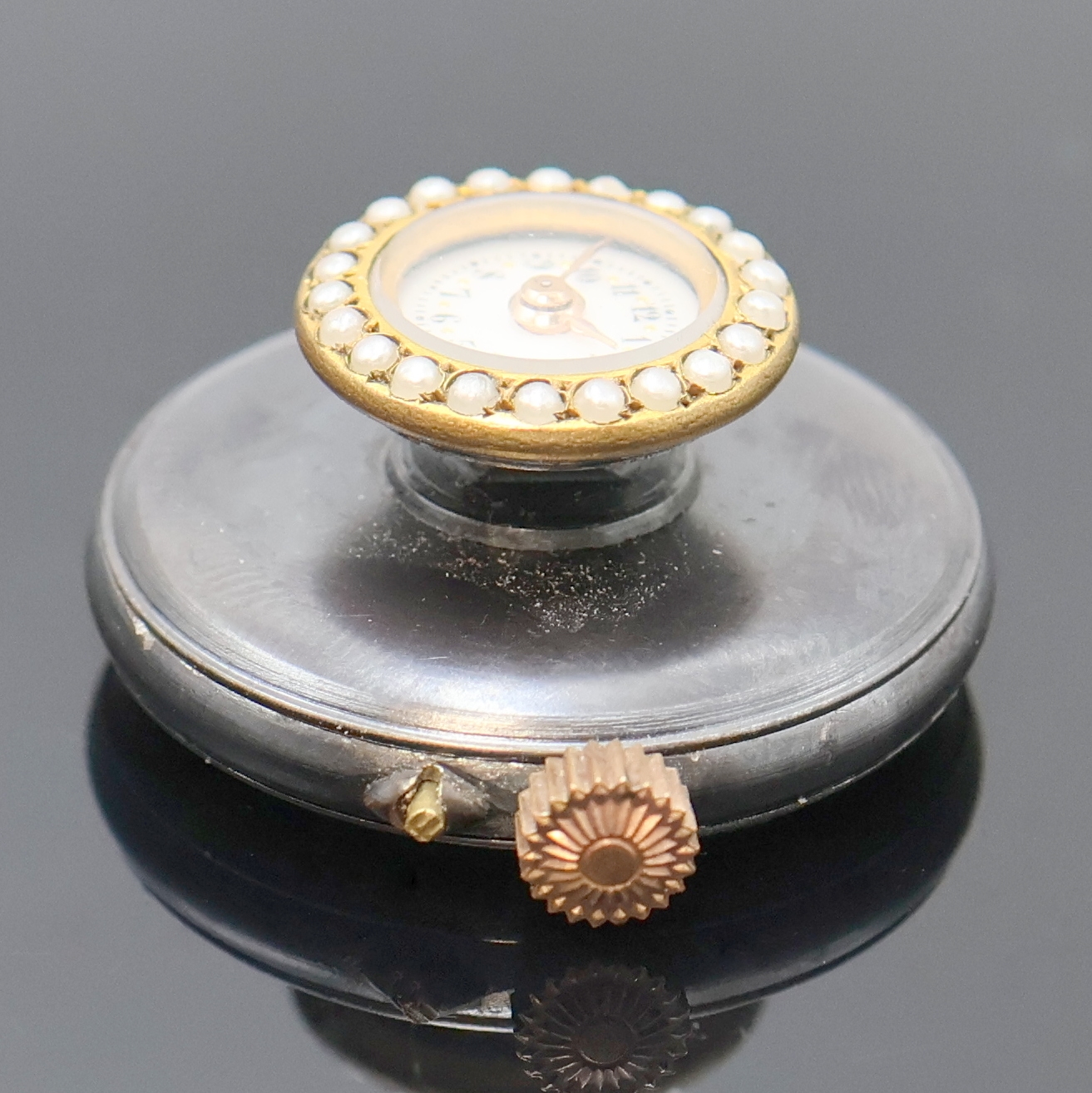 Detail a: Knopflochuhr im brüniertem Gehäuse, Schweiz um 1910, Boden aufgedr., Lünette m. Perlen bes., Emailzifferbl. m. arab. Zahlen, gold. Zeiger, verg. ...