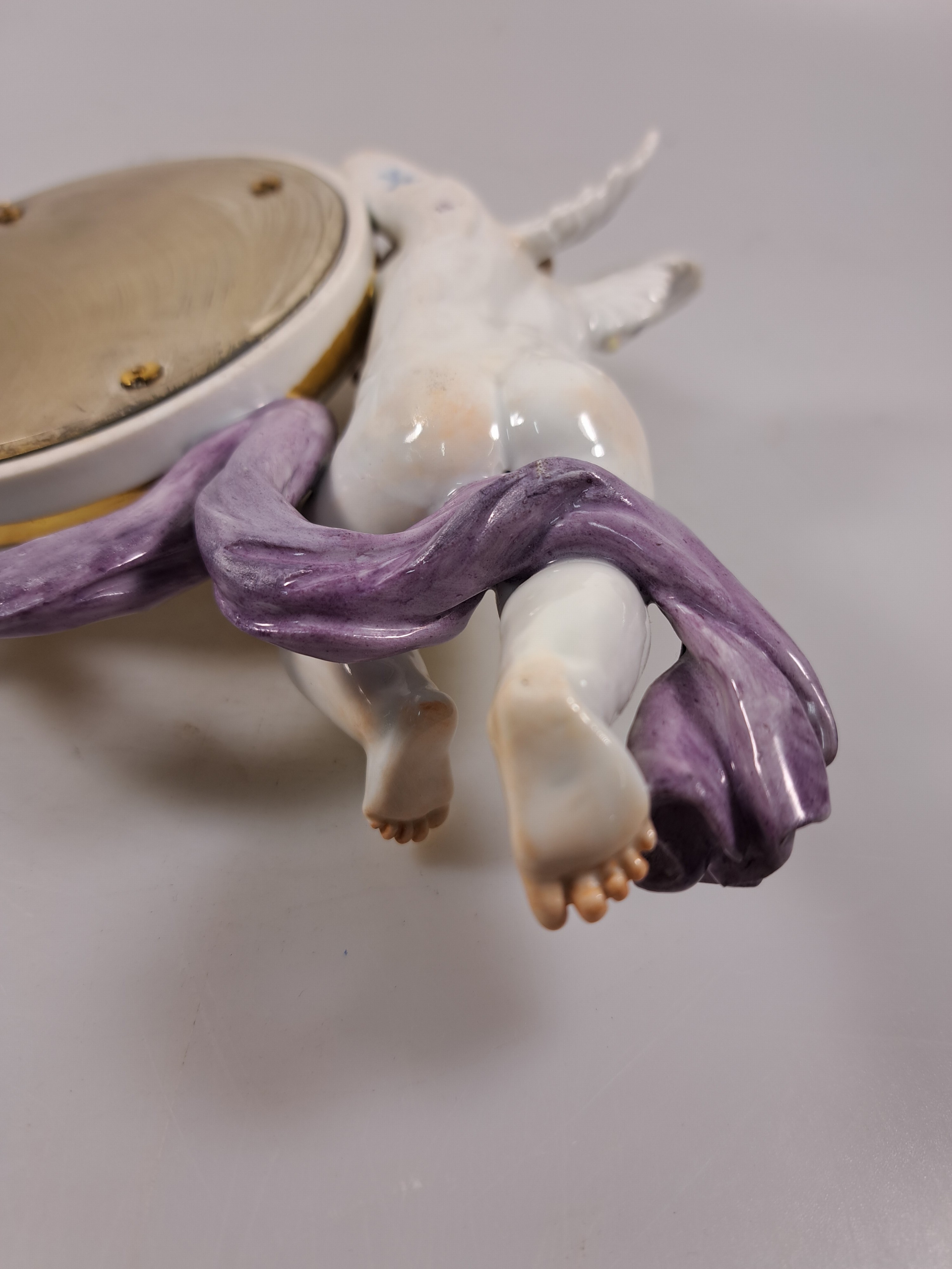 Detail h: Wandspiegel mit Amorette, Meissen um 1900, Porzellan, Amorette mit lilafarbener Schärpe hält eine ovalen Spiegel, applizierte Blüten, polychrom ...