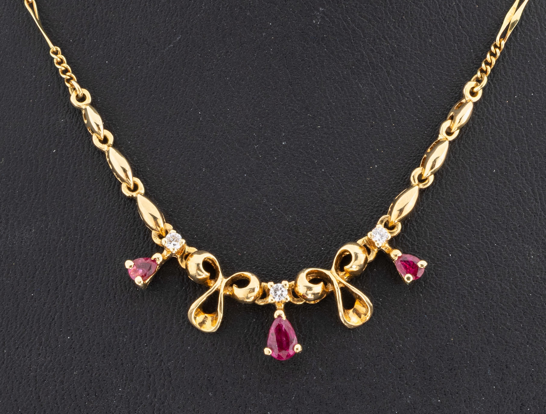 Detail a: 14 kt Gold Rubin-Brillant-Collier, GG 585/000, Mittelteil aus geschwungenen Elementen, 3 facett. Rubin-Tropfen zus. ca. 0.25 ct, 3 Brillanten zus. ...