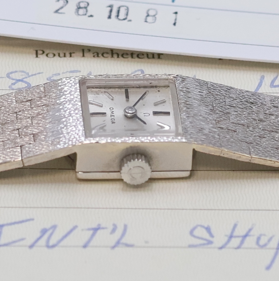 Detail d: OMEGA Damenarmbanduhr in WG 585/000, Schweiz verk. lt. beil. Garantie 09/1976, Handaufzug, orig. Goldband, Boden aufgedr., silb. Zifferbl. m. aufges. ...