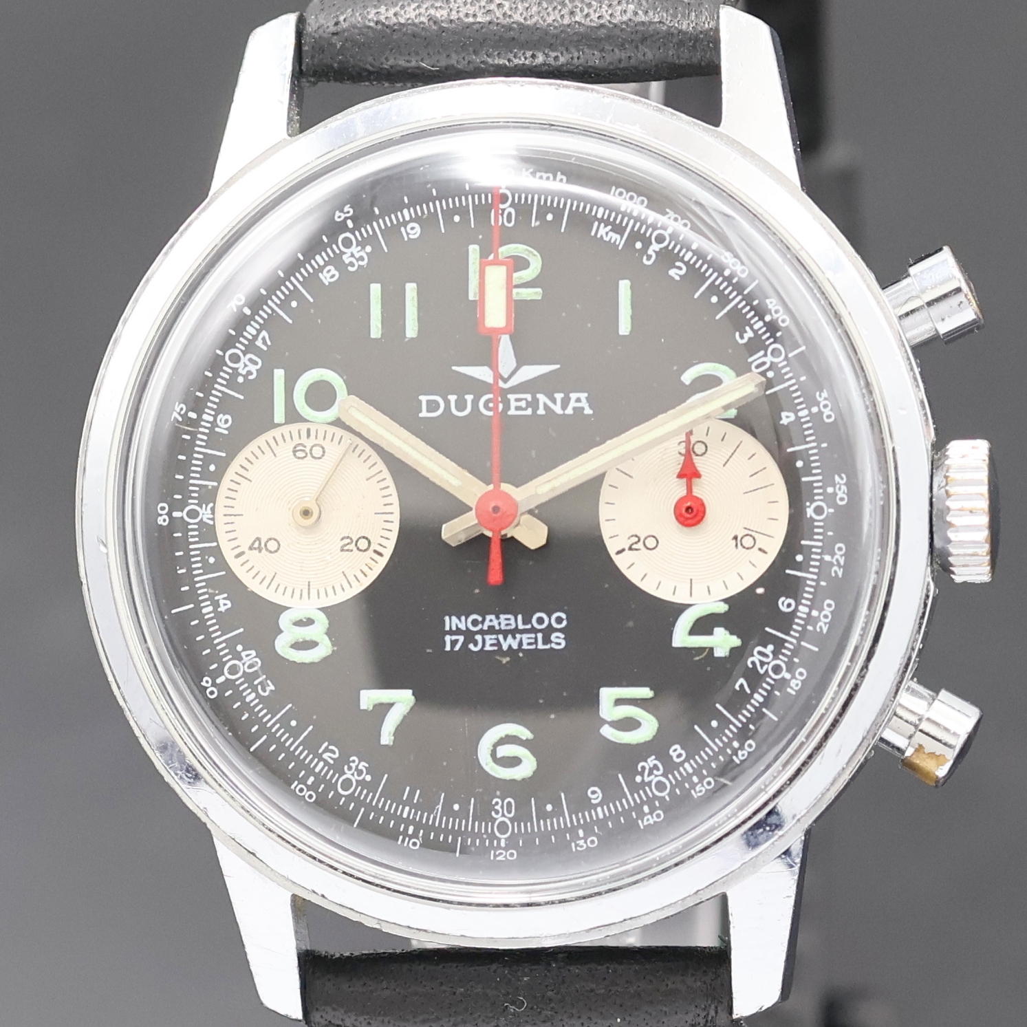Detail a: DUGENA Herrenarmbanduhr mit Chronograph, Handaufzug, Schweiz um 1970, verchr. Geh. m. verschr. Stahlboden, schwarzes Zifferbl. m. arab. Std., silb. ...