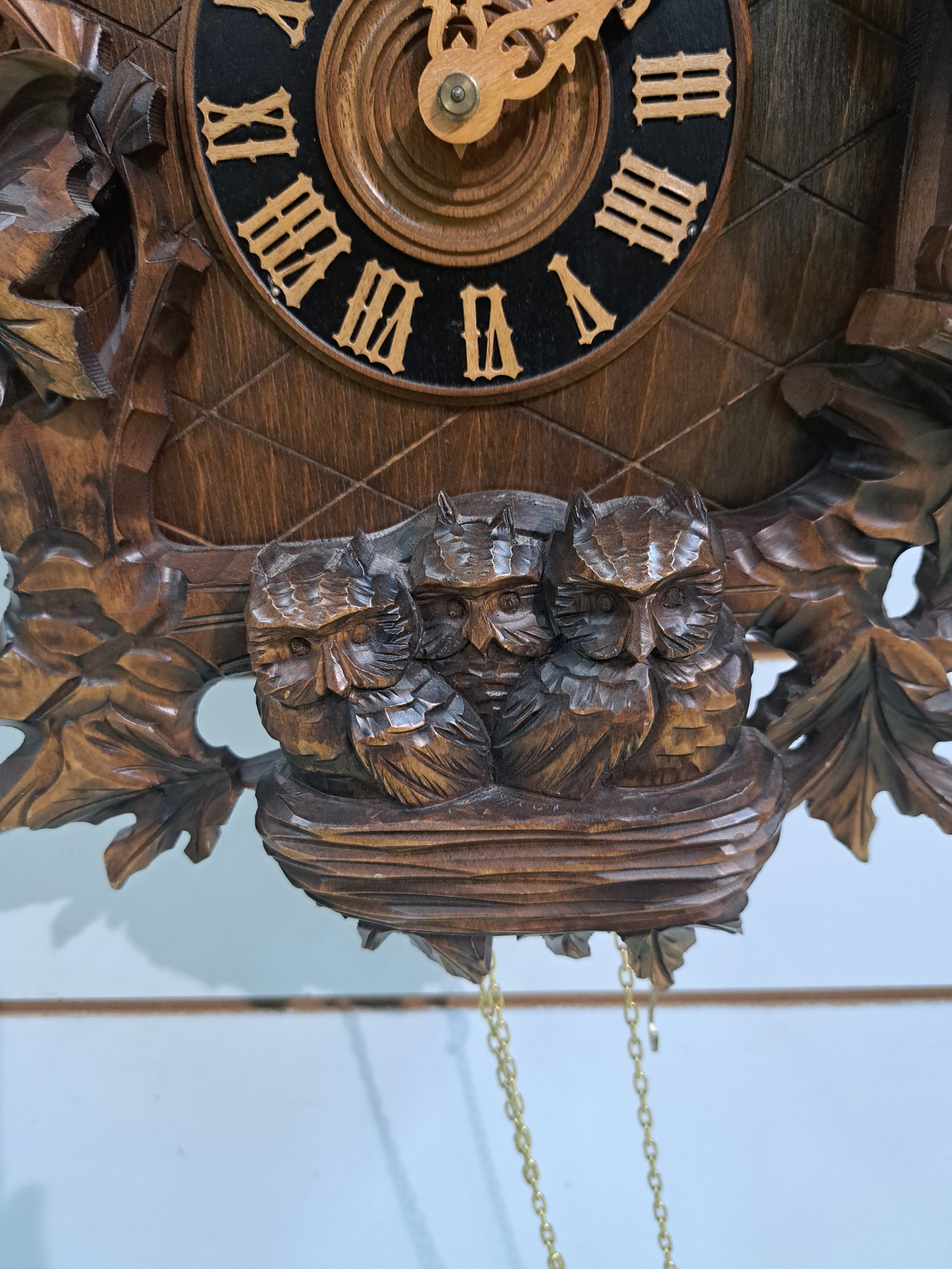 Detail e: Wanduhr mit Uhuruf und Musikspielwerk, Fa. Hönes, Titisee, um 1980, geschnitzte Front, mit plastischem Uhu und Blattwerk, orig. Aufsatz, seitliche ...