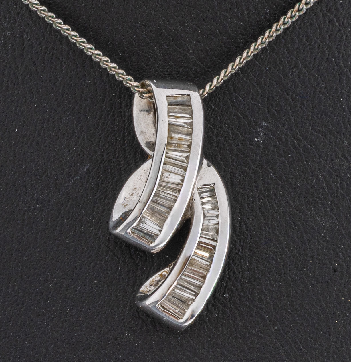 Detail a: 14 kt Gold Diamant-Anhänger, WG 585/000, geschwungen, 25 Diamant-Baguettes zus. ca. 1.10 ct Weiß/p, Hersteller Rodeo, an Kette WG 333/000, L. ca. ...
