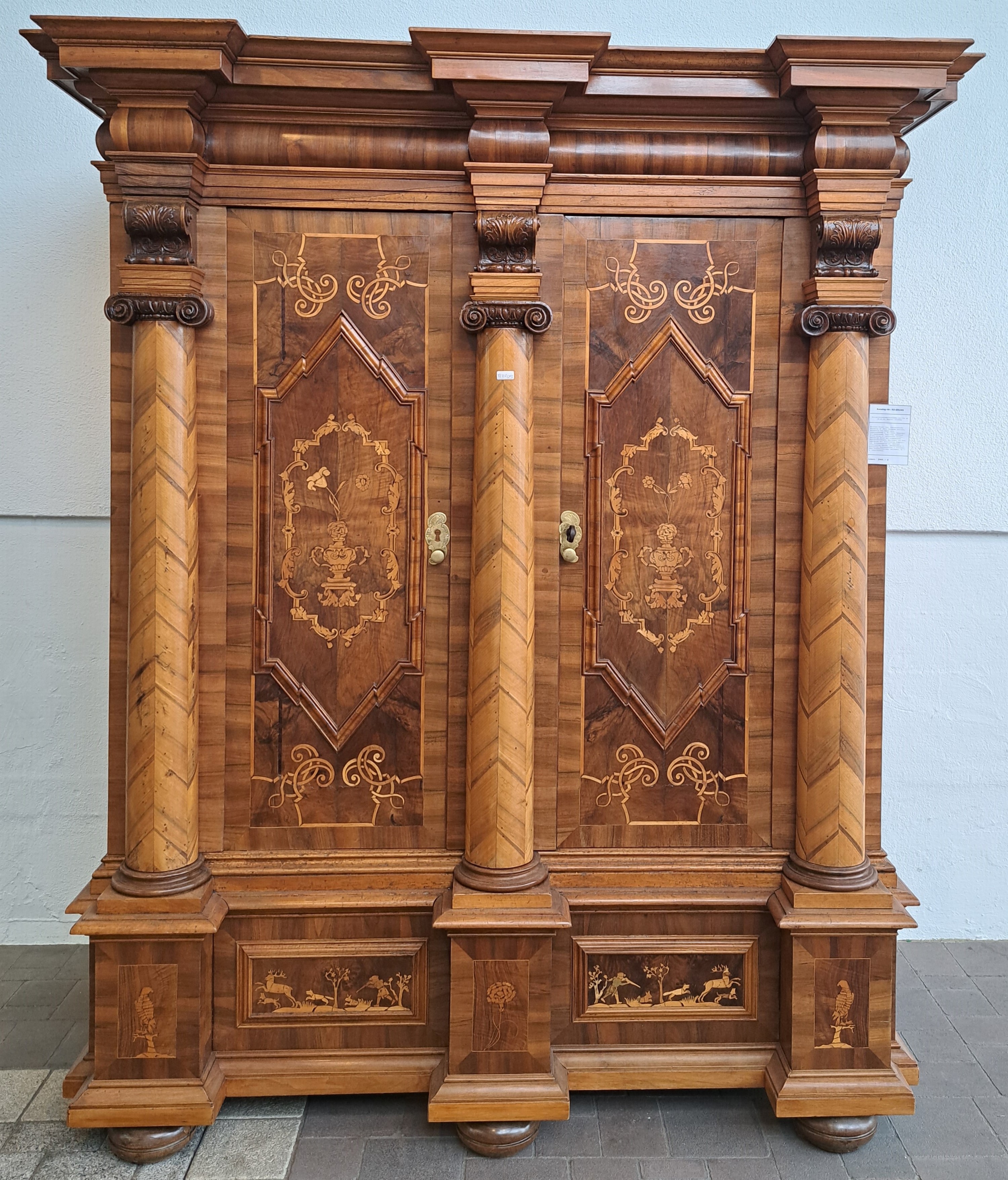Detail b: Barocker Prunk- bzw. Dielenschrank, Augsburg, um 1720, Nussbaum furniert, Marketerie mit Bandelwerk, Akanthusranken u. Rollwerk, Unterteil mit ...
