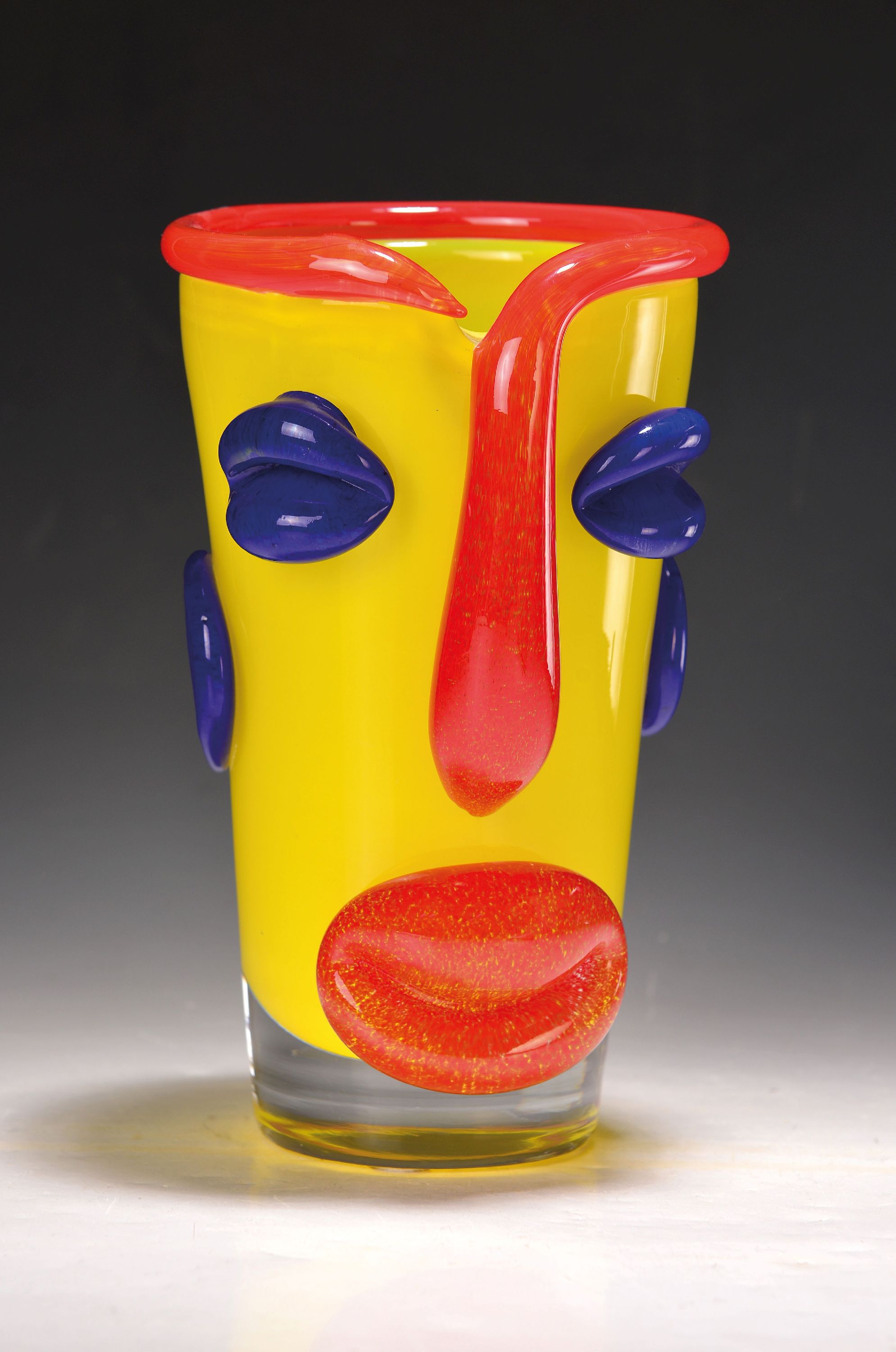 Detail k: Vase, Tschechien, 1980er Jahre, farbloses Glas mit opak-gelben Innenüberfang, aufgelegte blaue und rote Applikationen als Gesicht, H. ca. 26cm