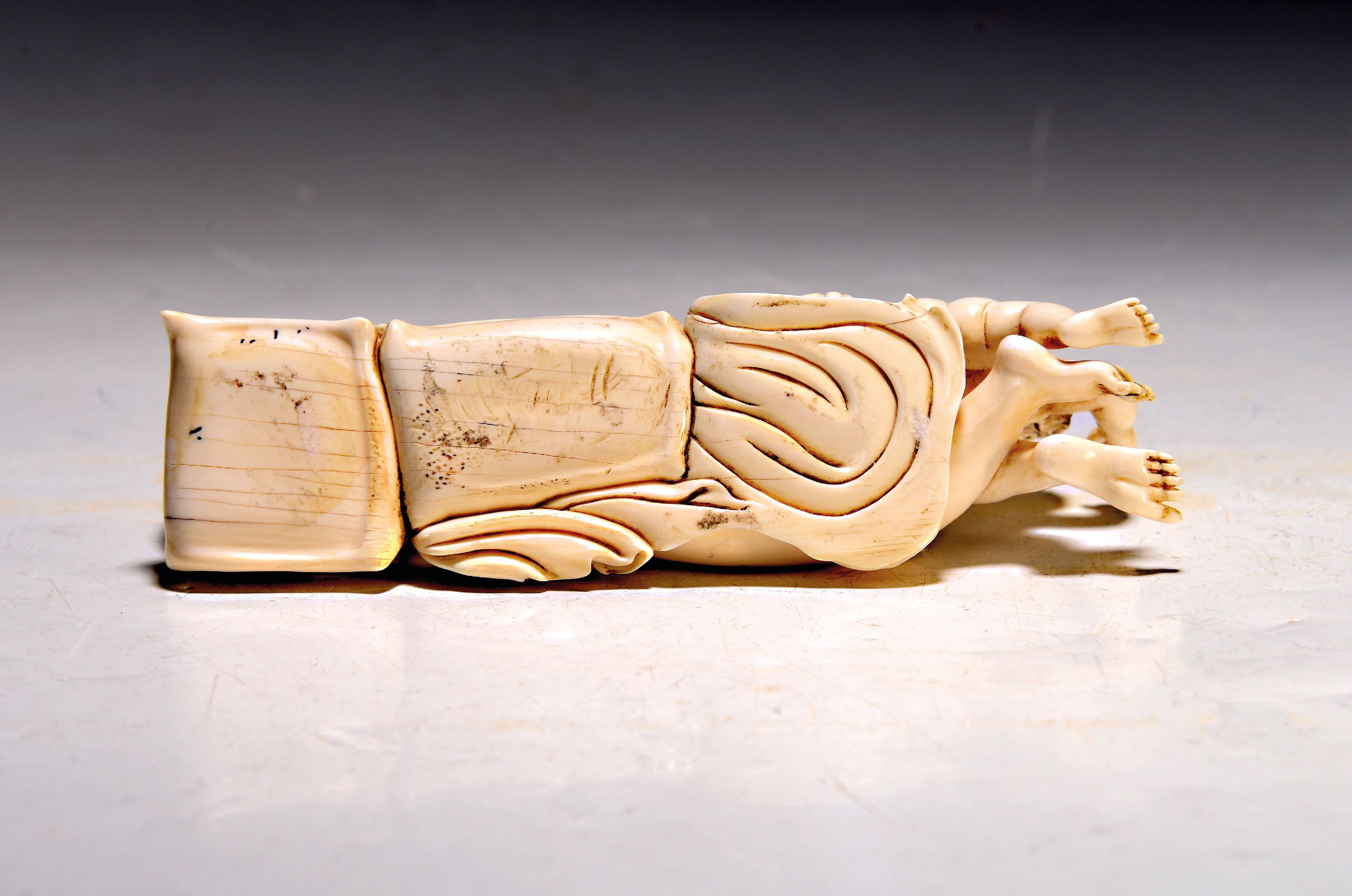Detail b: Elfenbeinfigur, wohl flämisch, 17./18. Jh., liegende Venus mit Amor, die Göttin hat ihren Kopf auf einem Kissen liegen, mit einer Hand verdeckt sie ...