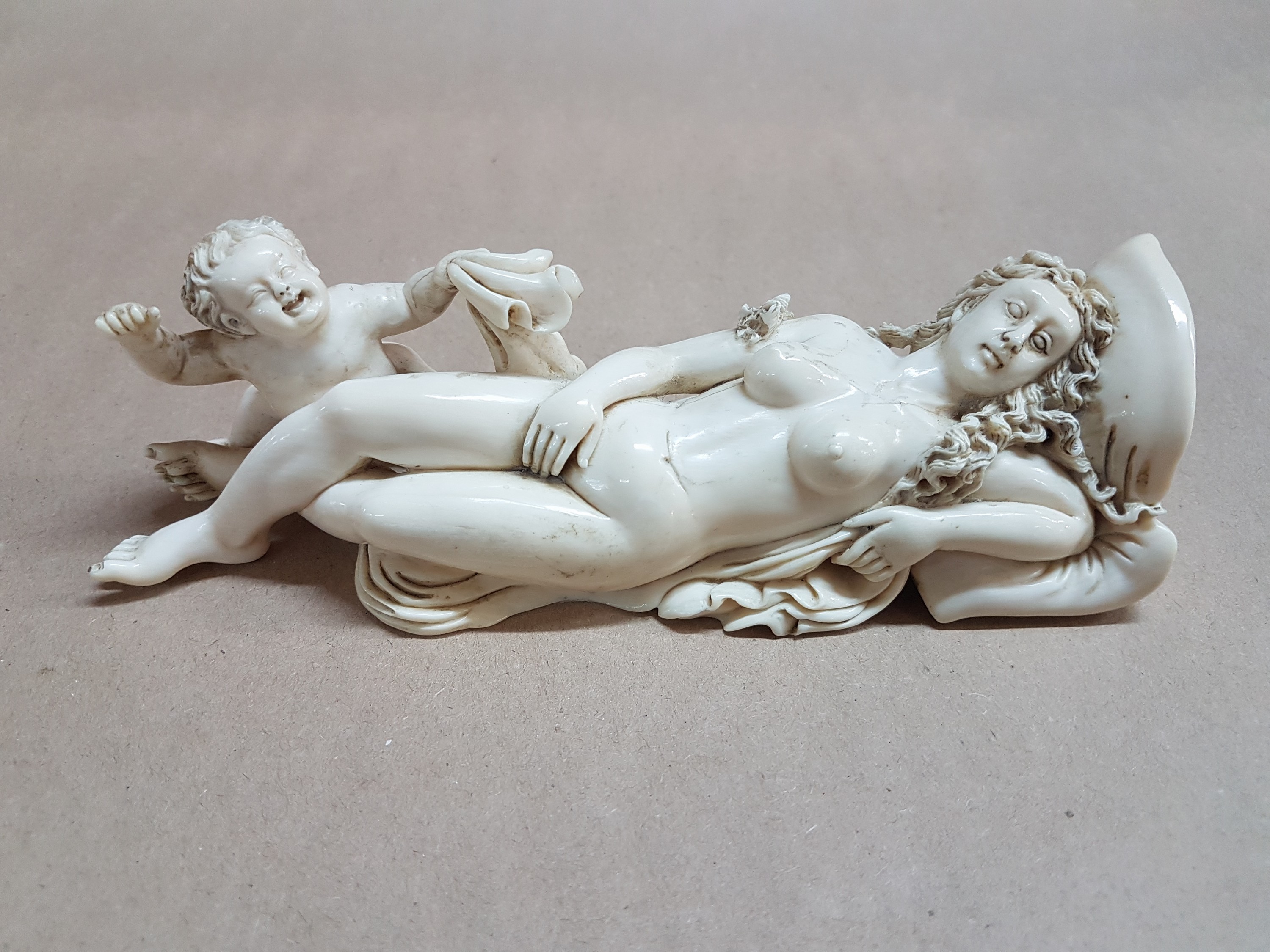 Detail e: Elfenbeinfigur, wohl flämisch, 17./18. Jh., liegende Venus mit Amor, die Göttin hat ihren Kopf auf einem Kissen liegen, mit einer Hand verdeckt sie ...