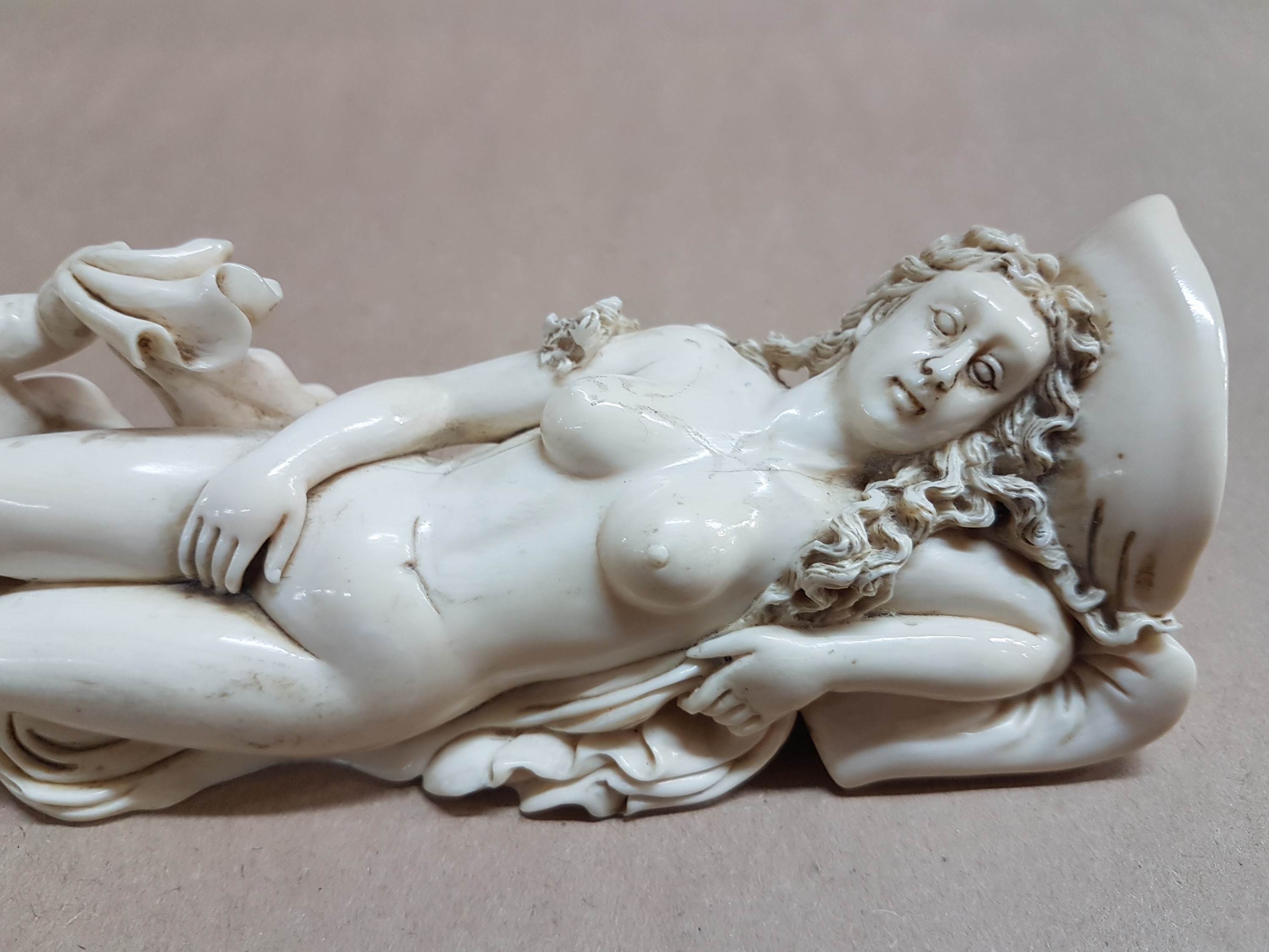 Detail g: Elfenbeinfigur, wohl flämisch, 17./18. Jh., liegende Venus mit Amor, die Göttin hat ihren Kopf auf einem Kissen liegen, mit einer Hand verdeckt sie ...