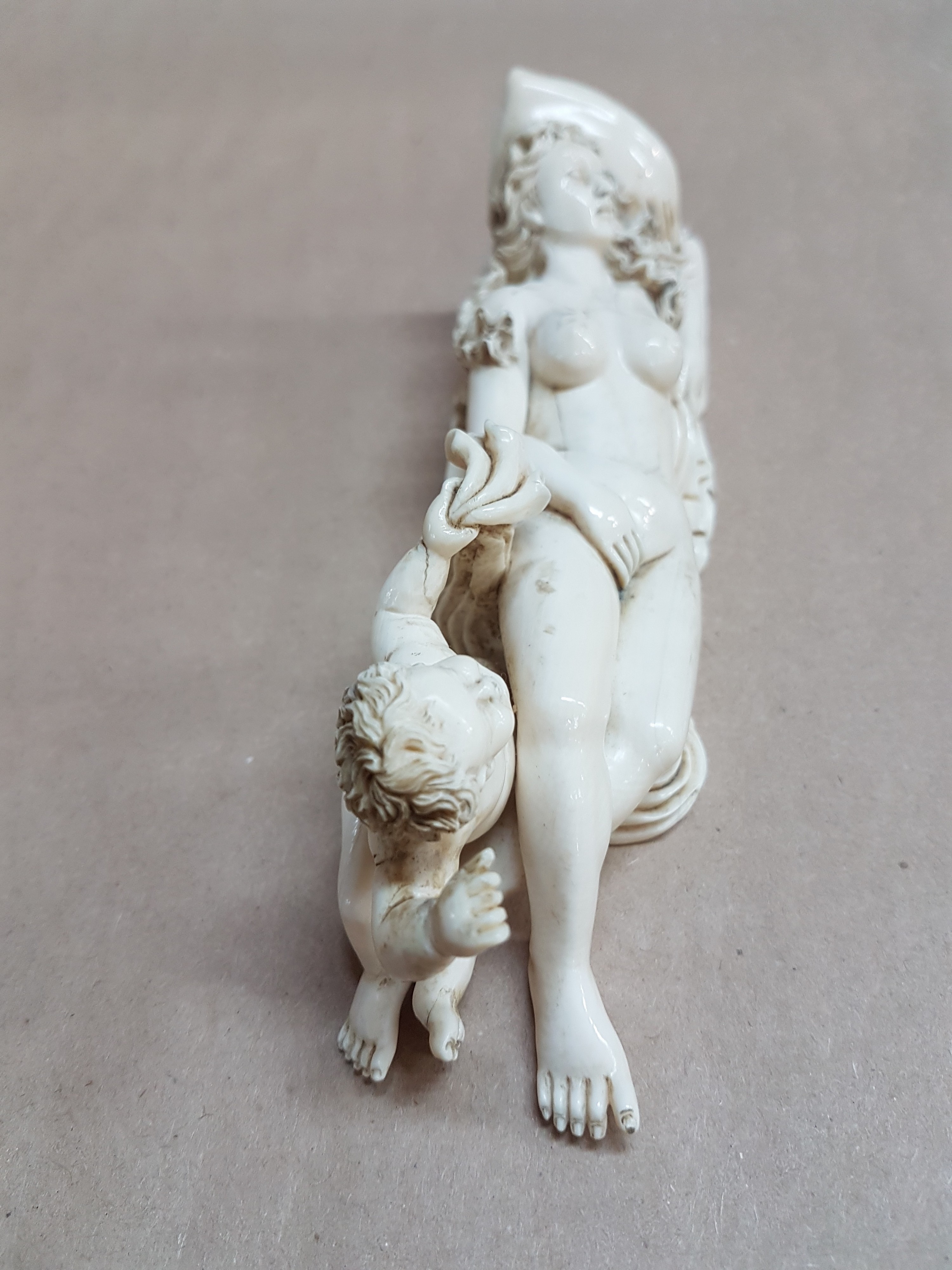 Detail l: Elfenbeinfigur, wohl flämisch, 17./18. Jh., liegende Venus mit Amor, die Göttin hat ihren Kopf auf einem Kissen liegen, mit einer Hand verdeckt sie ...