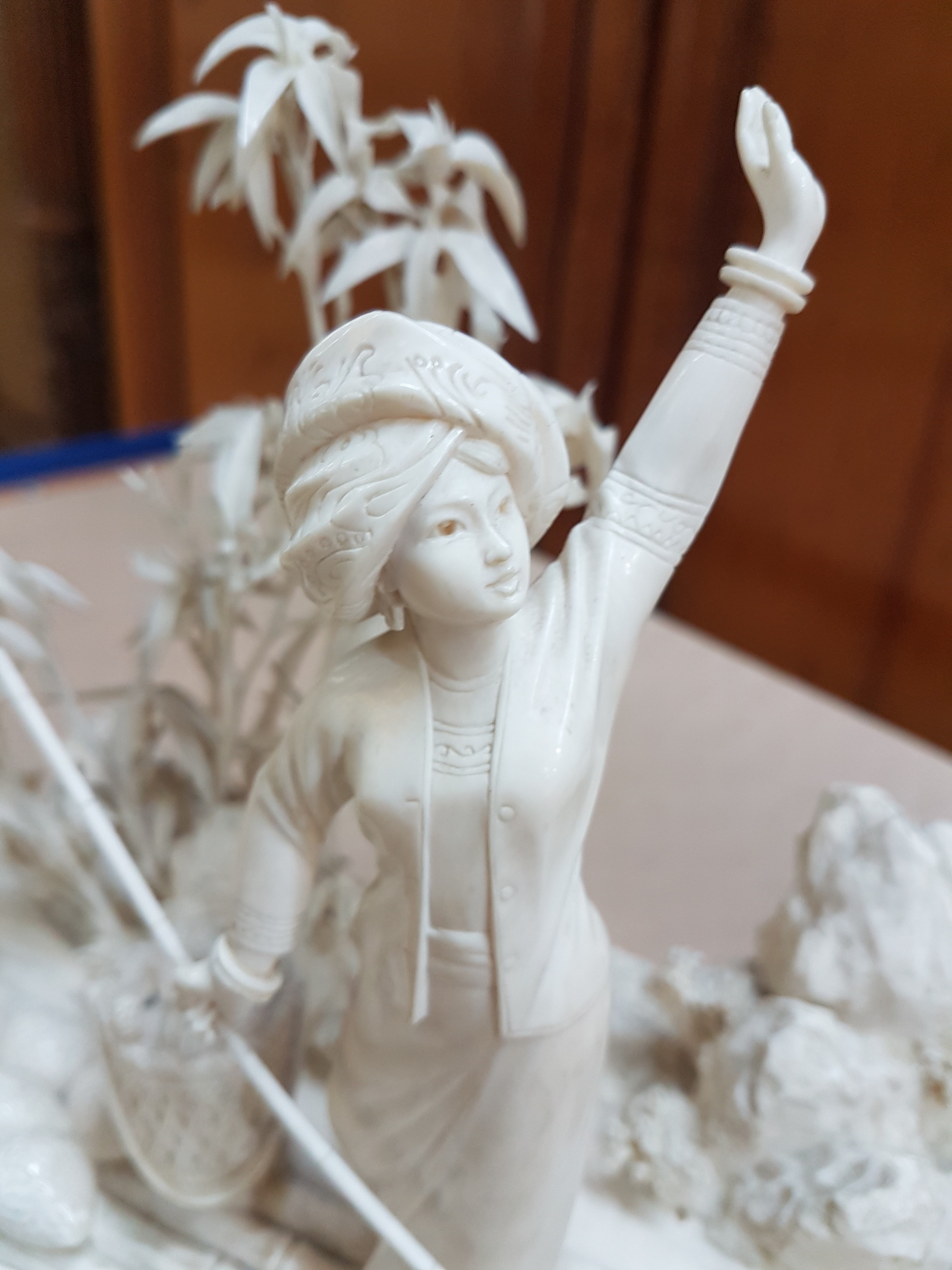 Detail p: Elfenbeinschnitzerei, China um 1900, Obstverkäuferin auf Floß, junge Frau mit erhobenem Arm und Stange, dahinter felsige Landschaft mit Bambus, ...