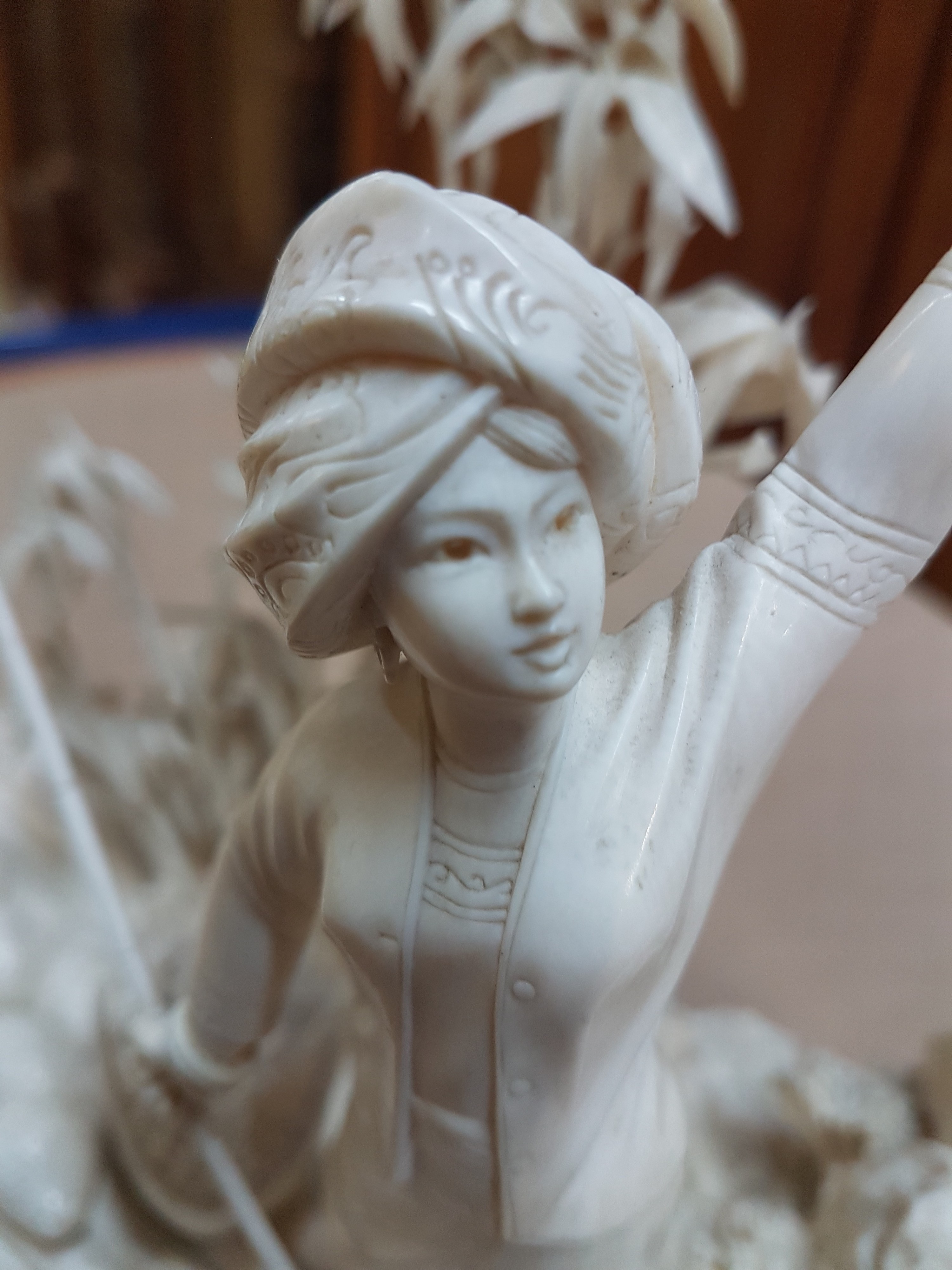 Detail q: Elfenbeinschnitzerei, China um 1900, Obstverkäuferin auf Floß, junge Frau mit erhobenem Arm und Stange, dahinter felsige Landschaft mit Bambus, ...