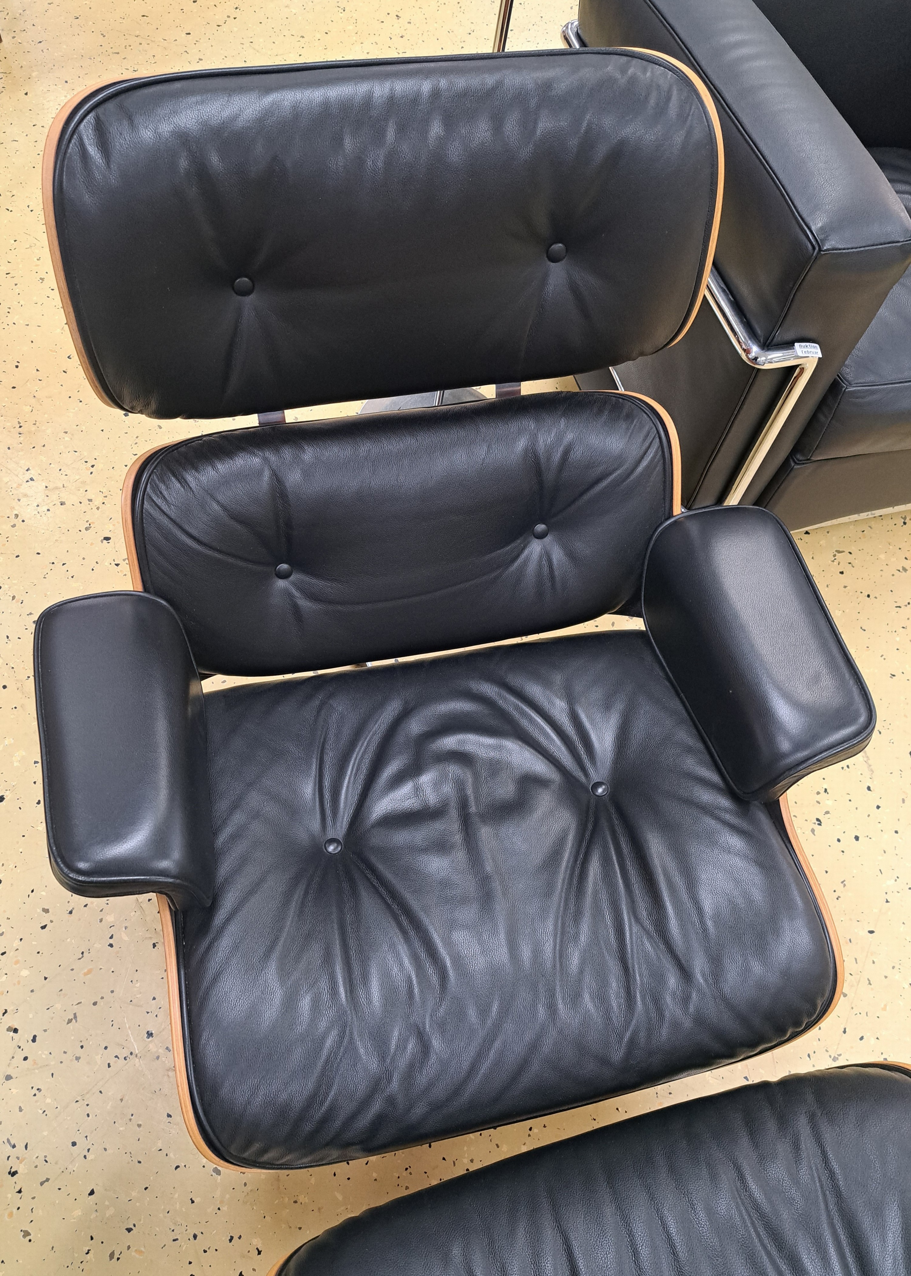 Detail a: Lounge-Chair mit Ottomane, Entw. Charles & Ray Eames von 1956, Ausführung Vitra, Sitzschale aus Schichtholz, Polsterung mit schwarzem Lederbezug, ...