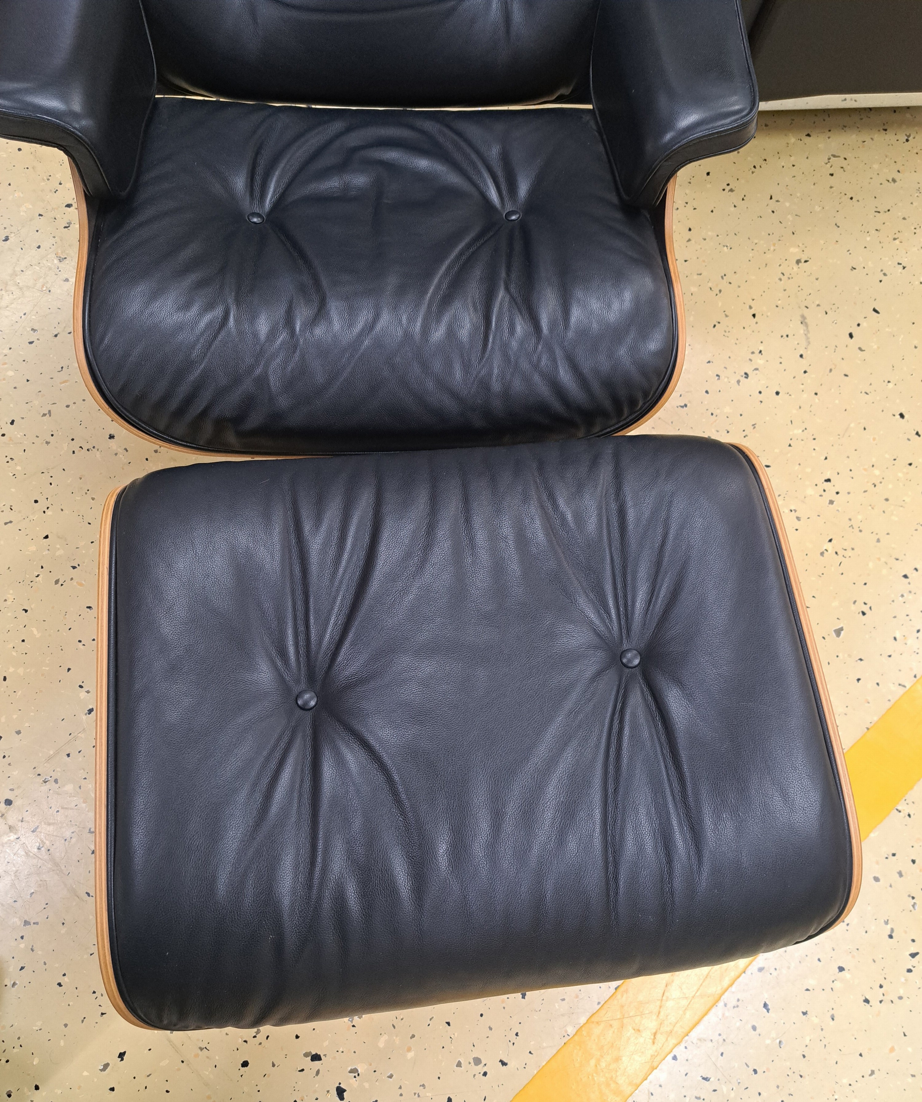 Detail b: Lounge-Chair mit Ottomane, Entw. Charles & Ray Eames von 1956, Ausführung Vitra, Sitzschale aus Schichtholz, Polsterung mit schwarzem Lederbezug, ...