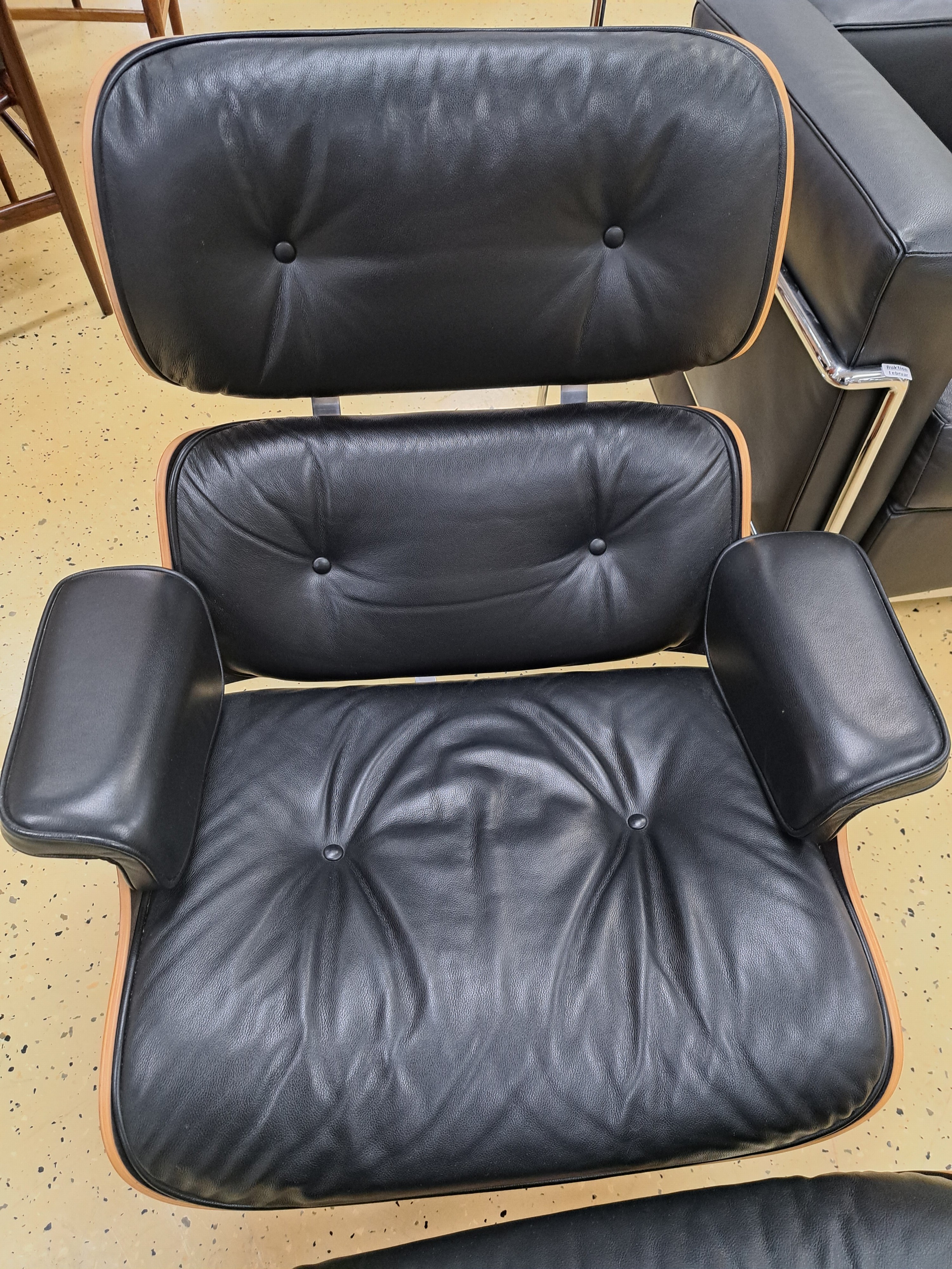 Detail d: Lounge-Chair mit Ottomane, Entw. Charles & Ray Eames von 1956, Ausführung Vitra, Sitzschale aus Schichtholz, Polsterung mit schwarzem Lederbezug, ...