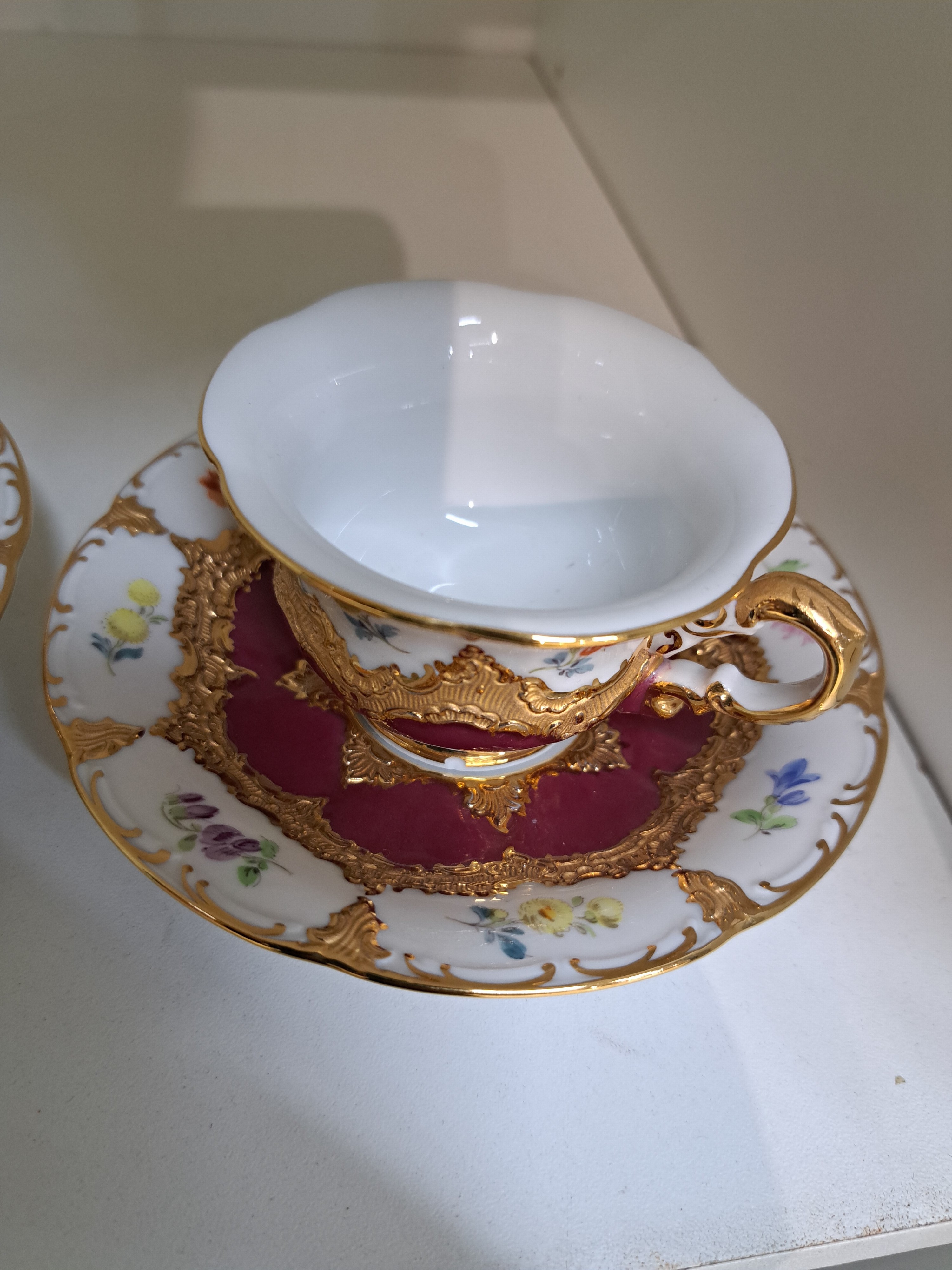 Detail b: Zwei Mokkatassen mit Untertassen, Meissen, 2.H.20.Jh., B-Form, purpurroter Fond, bemalt im Dekor gestreute Blümchen, Matt- u. Glanzvergoldung, 2. ...