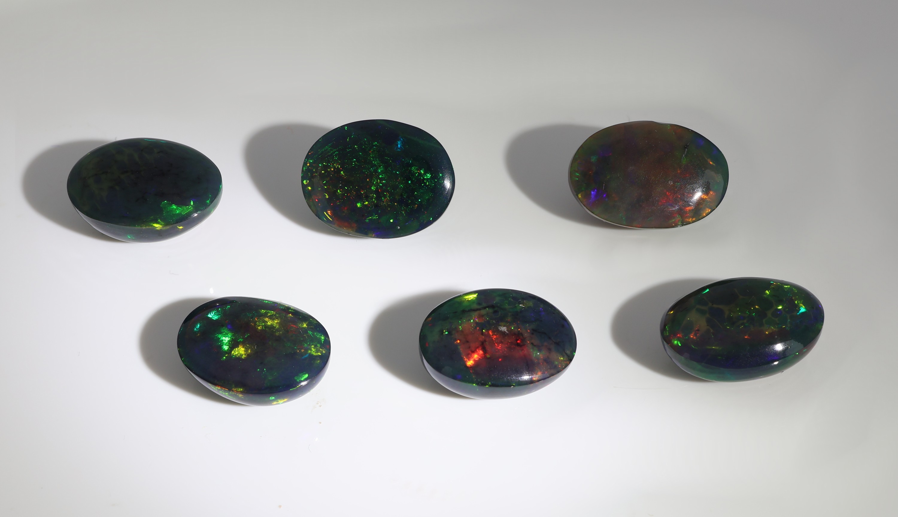 Detail b: Lot 6 lose schwarze Opale, zus. ca. 25.49 ct, ovale Cabochons in versch. Größen, intensives Farbspiel in Grün, Rot und Blau