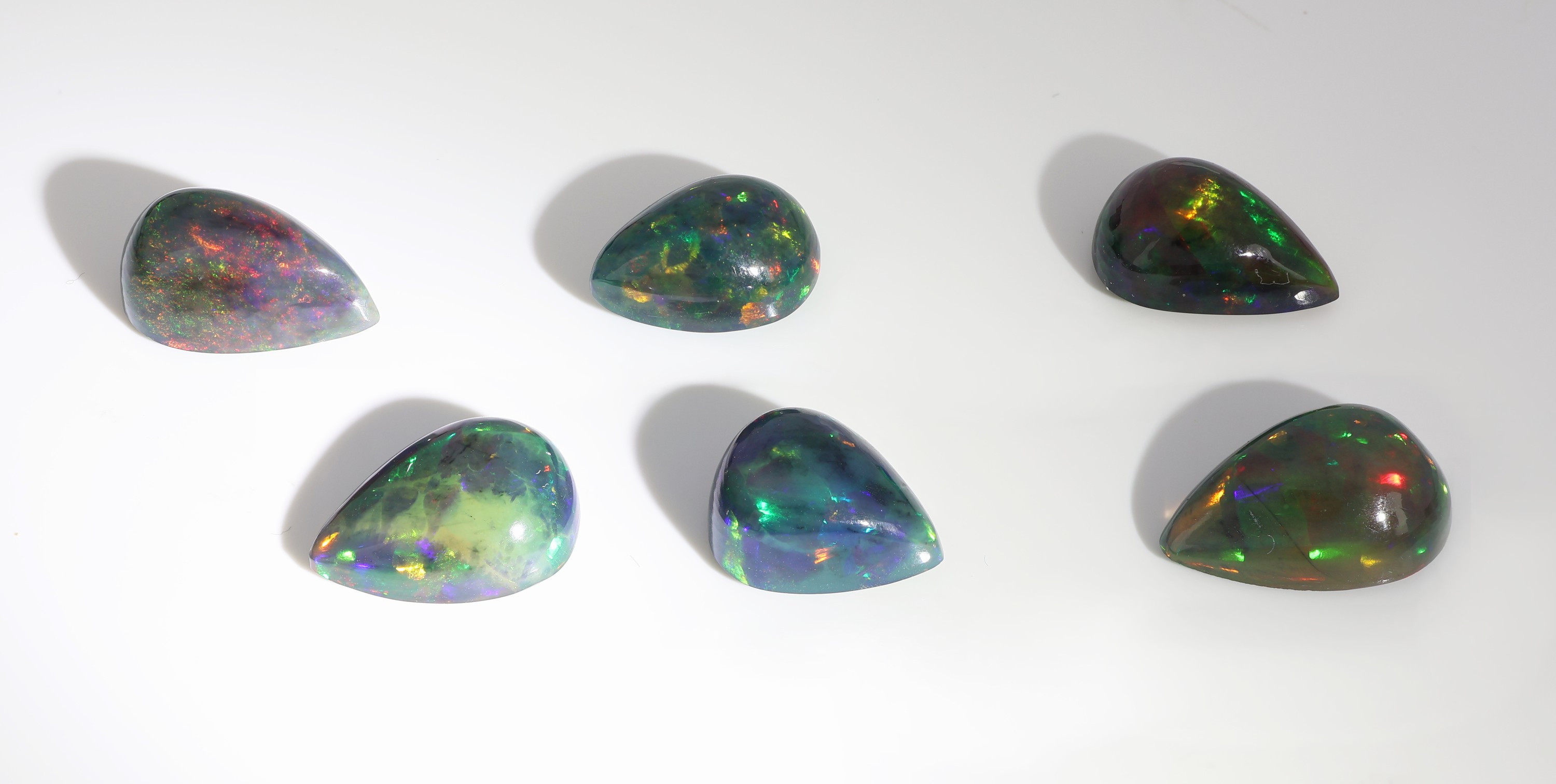 Detail b: Lot 6 lose schwarze Opale, zus. ca. 17.95 ct, tropfenf. Cabochons in versch. Größen, intensives Farbspiel in Grün, Rot und Blau
