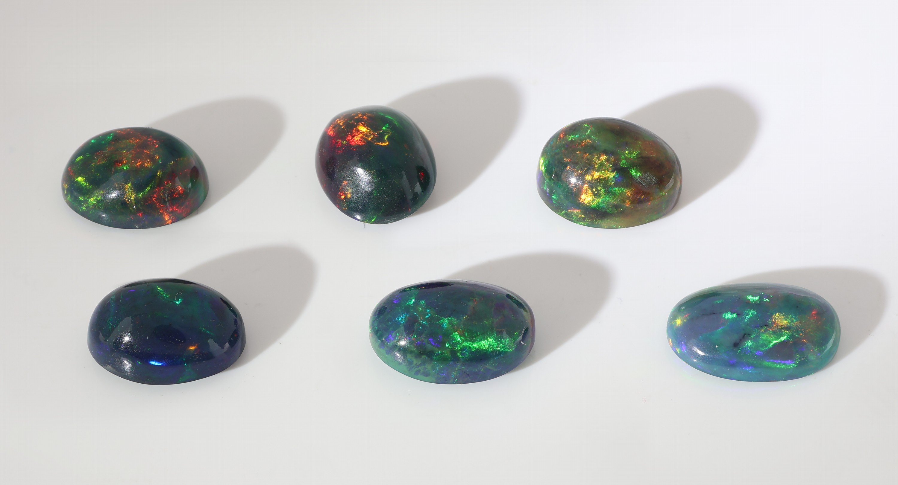 Detail b: Lot 6 lose schwarze Opale, zus. ca. 18.93 ct, ovale Cabochons in versch. Größen, intensives Farbspiel