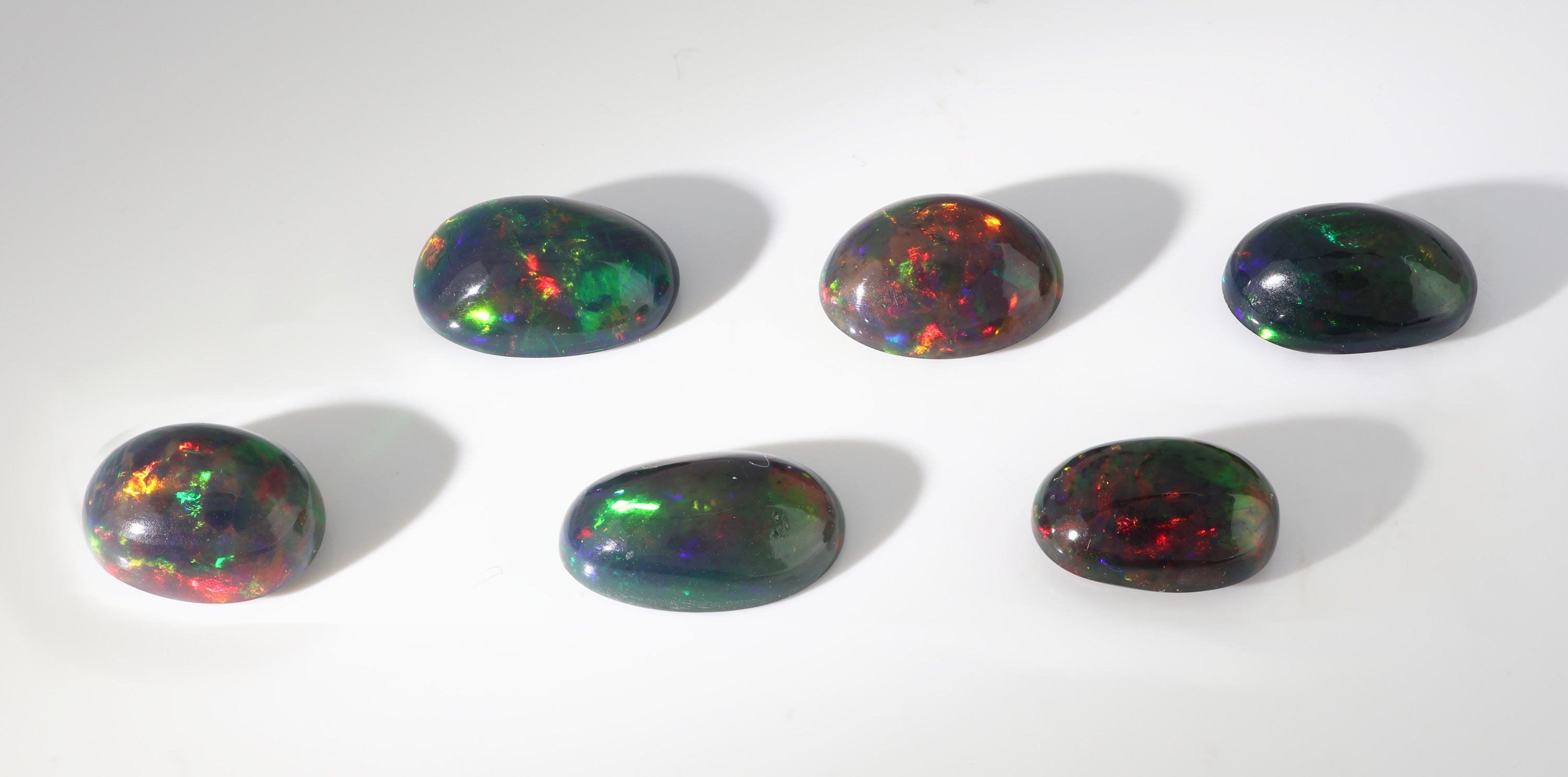 Detail b: Lot 6 lose schwarze Opale, zus. ca. 18.44 ct, ovale Cabochons in versch. Größen, intensives Farbspiel