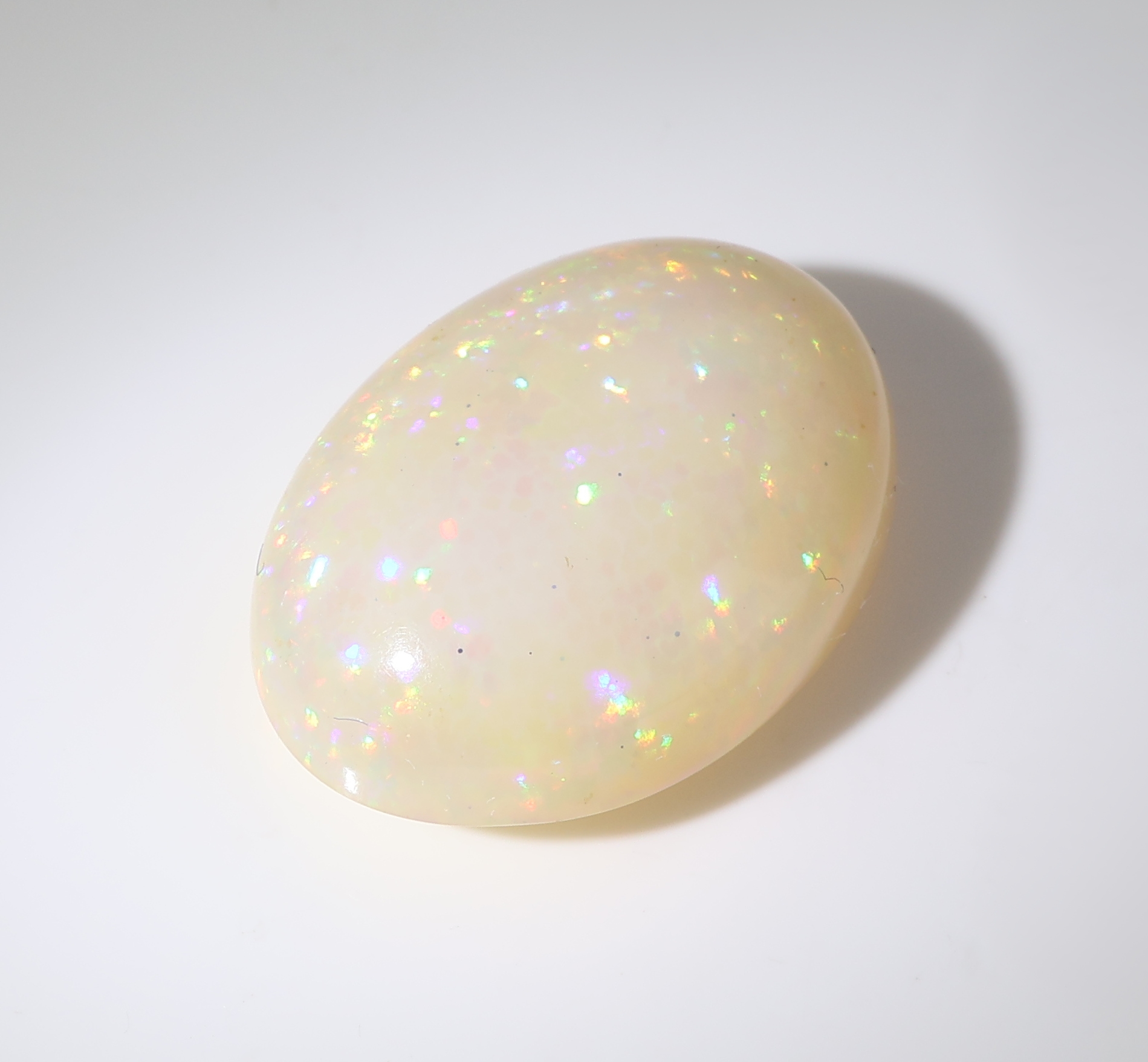 Detail b: Loser weißer Opal, ca. 9.52 ct, ovaler Cabochon, Farbspiel in Grün, Gelb und Blau, ca. 17.31 x 12.99 x 7.33 mm, Herkunft Äthiopien