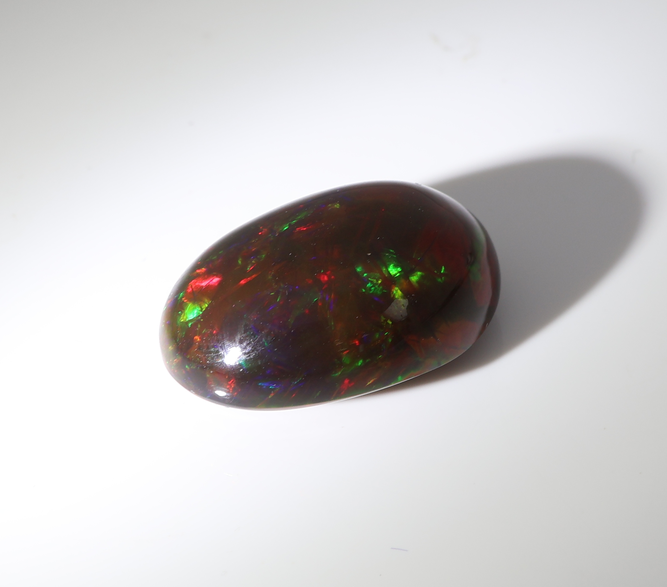 Detail b: Loser schwarzer Opal, ca. 10.91 ct, ovaler Cabochon, Farbspiel in Grün, Rot und Blau