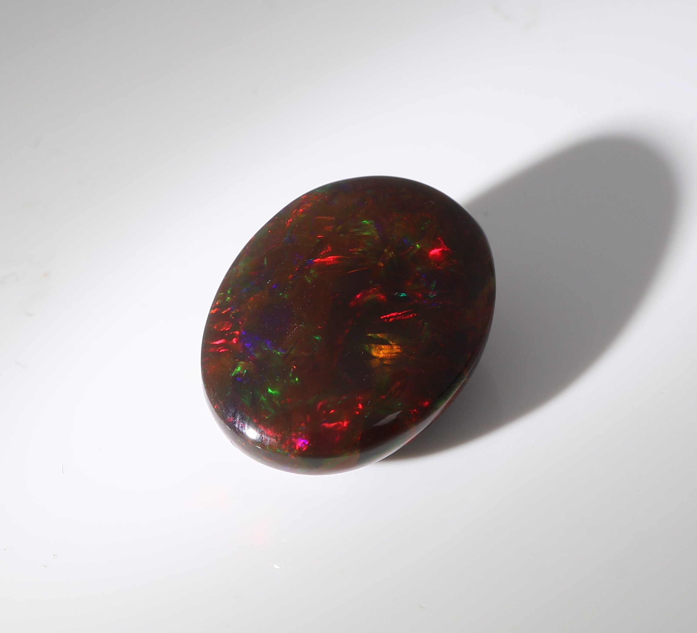 Detail c: Loser schwarzer Opal, ca. 10.91 ct, ovaler Cabochon, Farbspiel in Grün, Rot und Blau