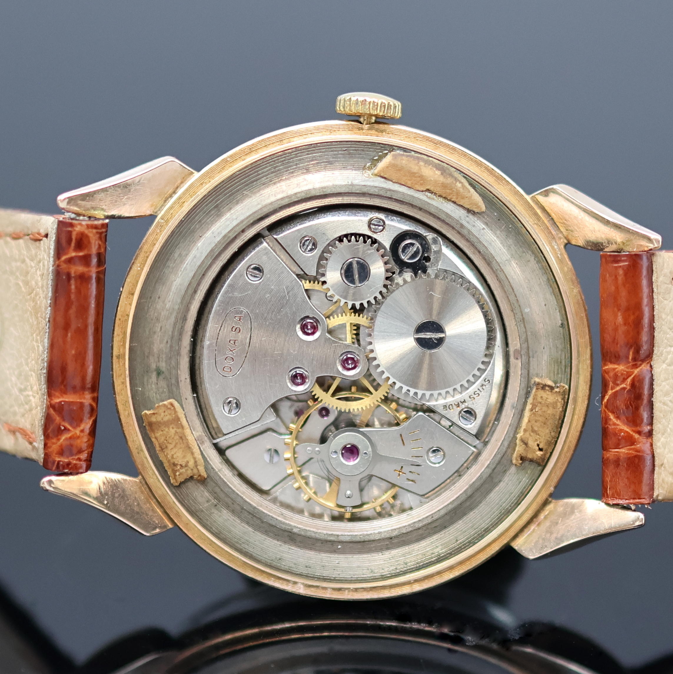 Detail e: DOXA Armbanduhr in RG 585/000, Schweiz um 1960, Handaufzug, tropfenförm. Anstöße, Boden aufgedr., silb. Zifferbl. m. gold. Std.-Ind. u. Zahlen, ...