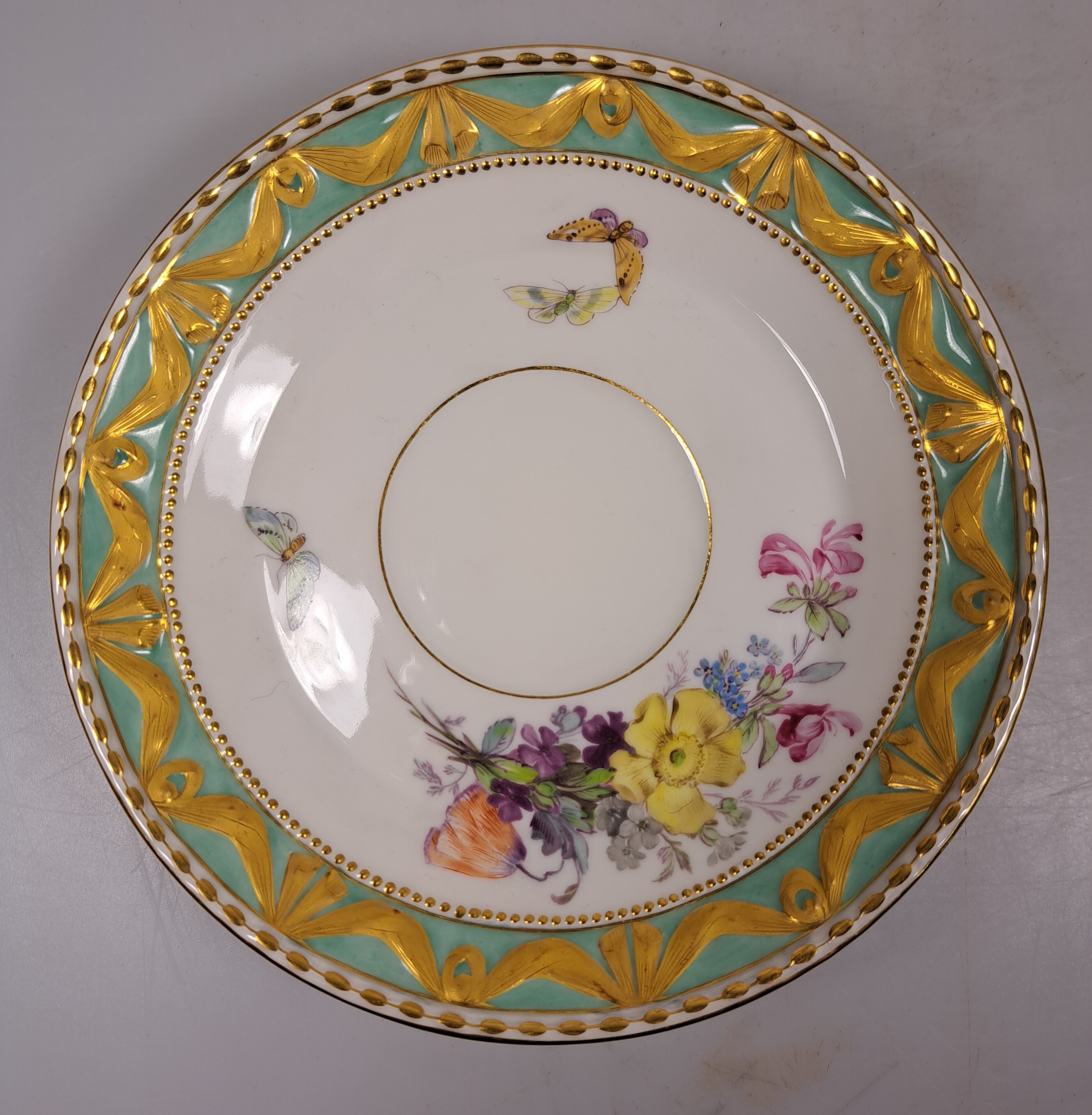 Detail a: Tasse mit Untertasse, KPM Berlin, Modell Kurland, Rand türkisfarben mit Matt- und Glanzvergoldung, bunte Blumenmalerei mit Insekten, H. ca. 5cm