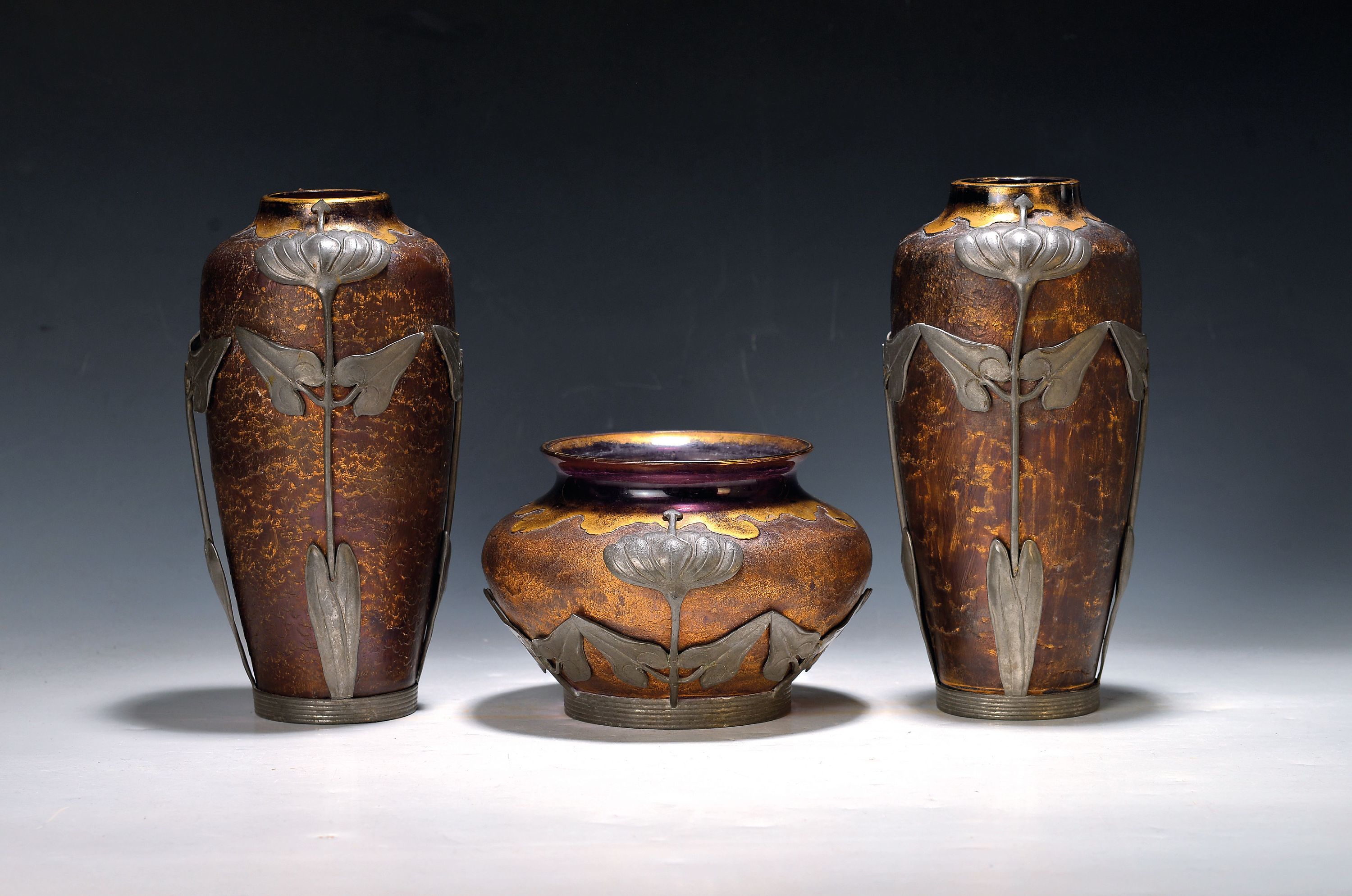 Dreiteiliges Vasenset, Jugendstil, Zinnmontur wohl van Hauten, um 1900/10, lilafarbenes Glas mit Goldstaffage, geätzt, florale Zinnmontur auf der ...