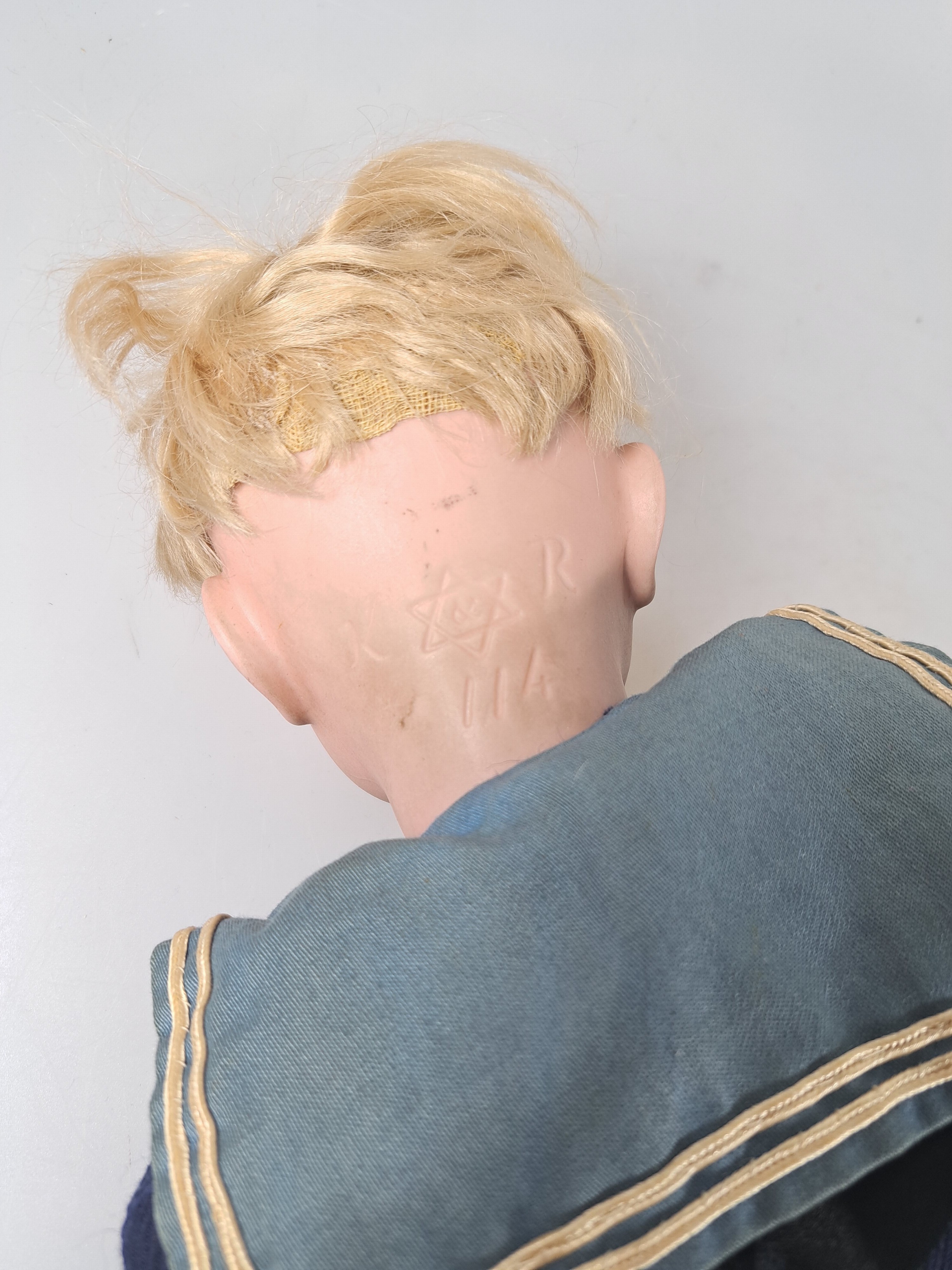 Detail b: Porzellankopfpuppe, Kämmer & Reinhard, 114, um 1909, braune Schlafaugen, geschlossener Mund, blonde Mohairperücke, Gliederkörper, l. Gebr.-spuren, ...