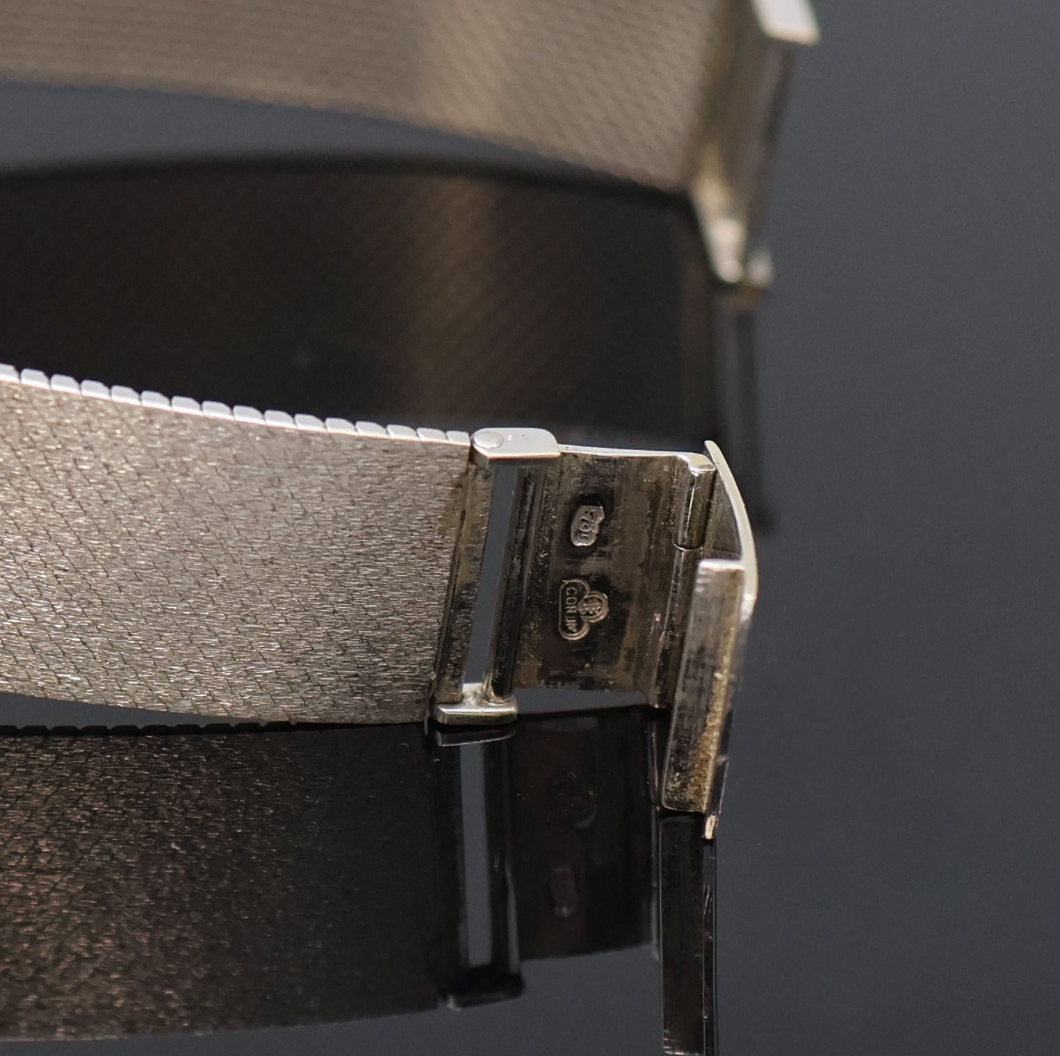 Detail b: CORUM Armbanduhr in WG 750/000, Schweiz um 1960, Handaufzug, orig. Goldband, Boden aufgedr., graues Zifferbl. m. aufges. Std.- Ind., silb. Zeiger, ...