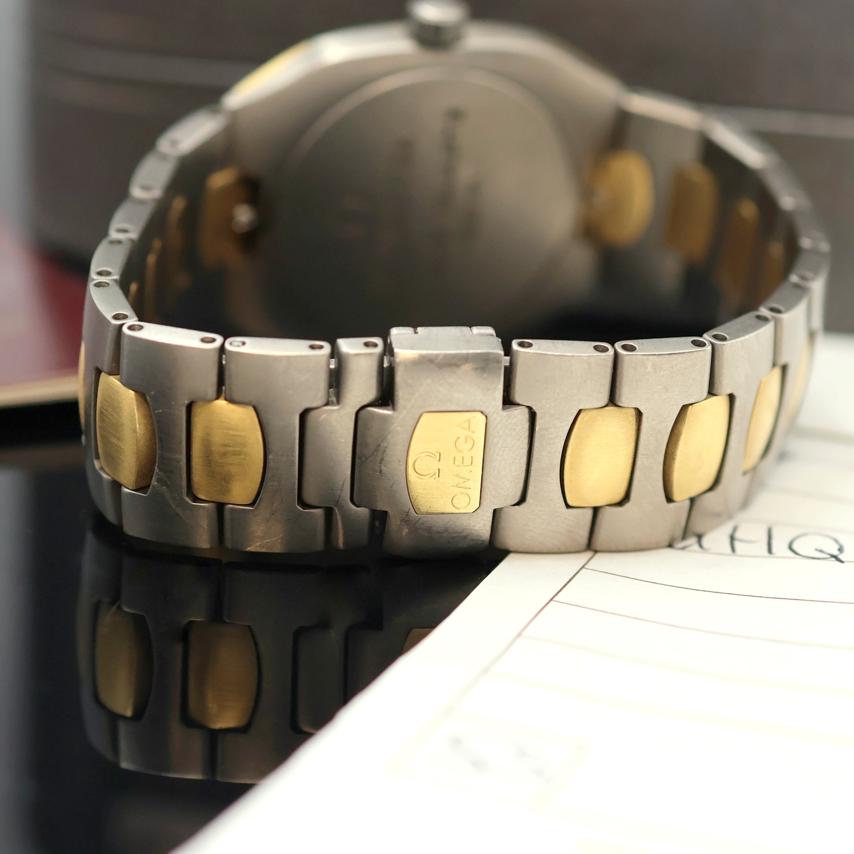 Detail d: OMEGA Seamaster Polaris Armbanduhr in Titan Referenz 196.0291/396.0981, Schweiz um 1990, quarz, Geh. Gold-intarsiert, orig. Gliederband m. dopp. ...