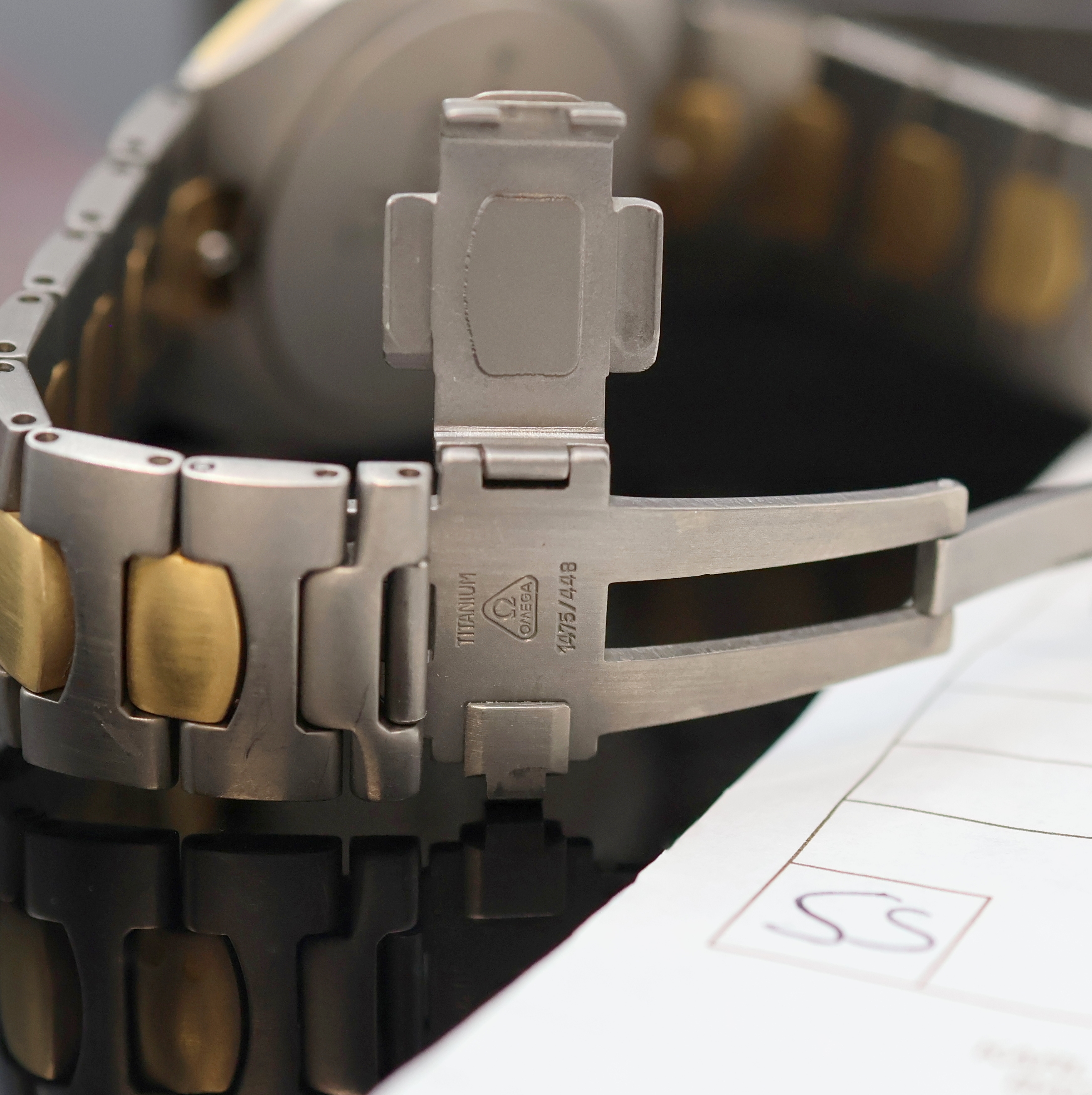 Detail e: OMEGA Seamaster Polaris Armbanduhr in Titan Referenz 196.0291/396.0981, Schweiz um 1990, quarz, Geh. Gold-intarsiert, orig. Gliederband m. dopp. ...