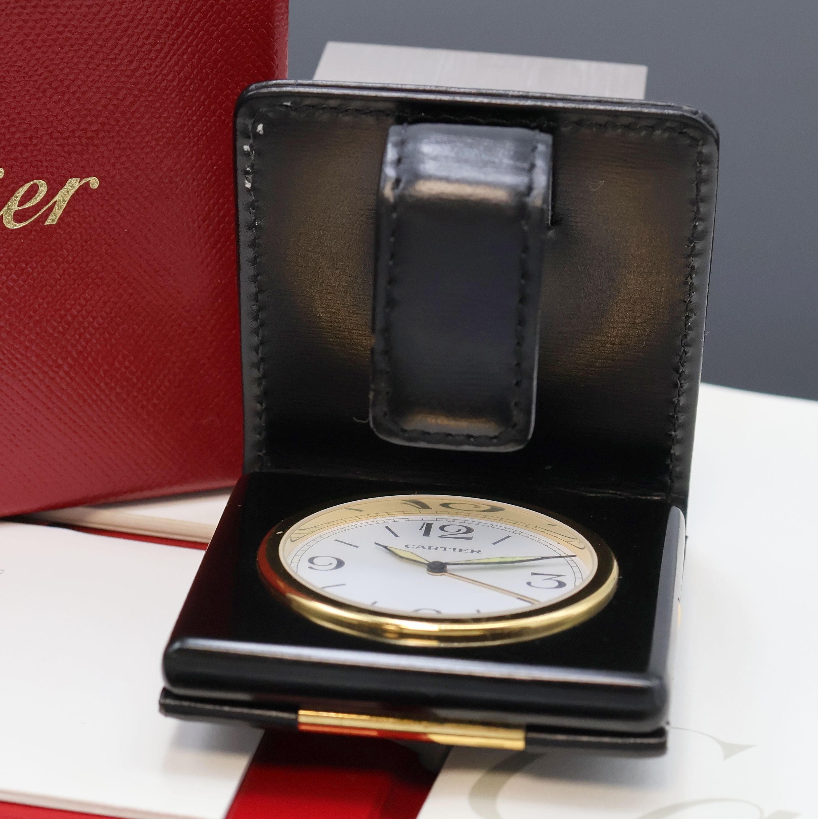 Detail b: CARTIER kleiner Reisewecker, Schweiz verk. lt. beil. Pap. 11/1999, quarz, verg. Geh. im schwarzen Rahmen und Lederetui, Wecker durch drücken der ...