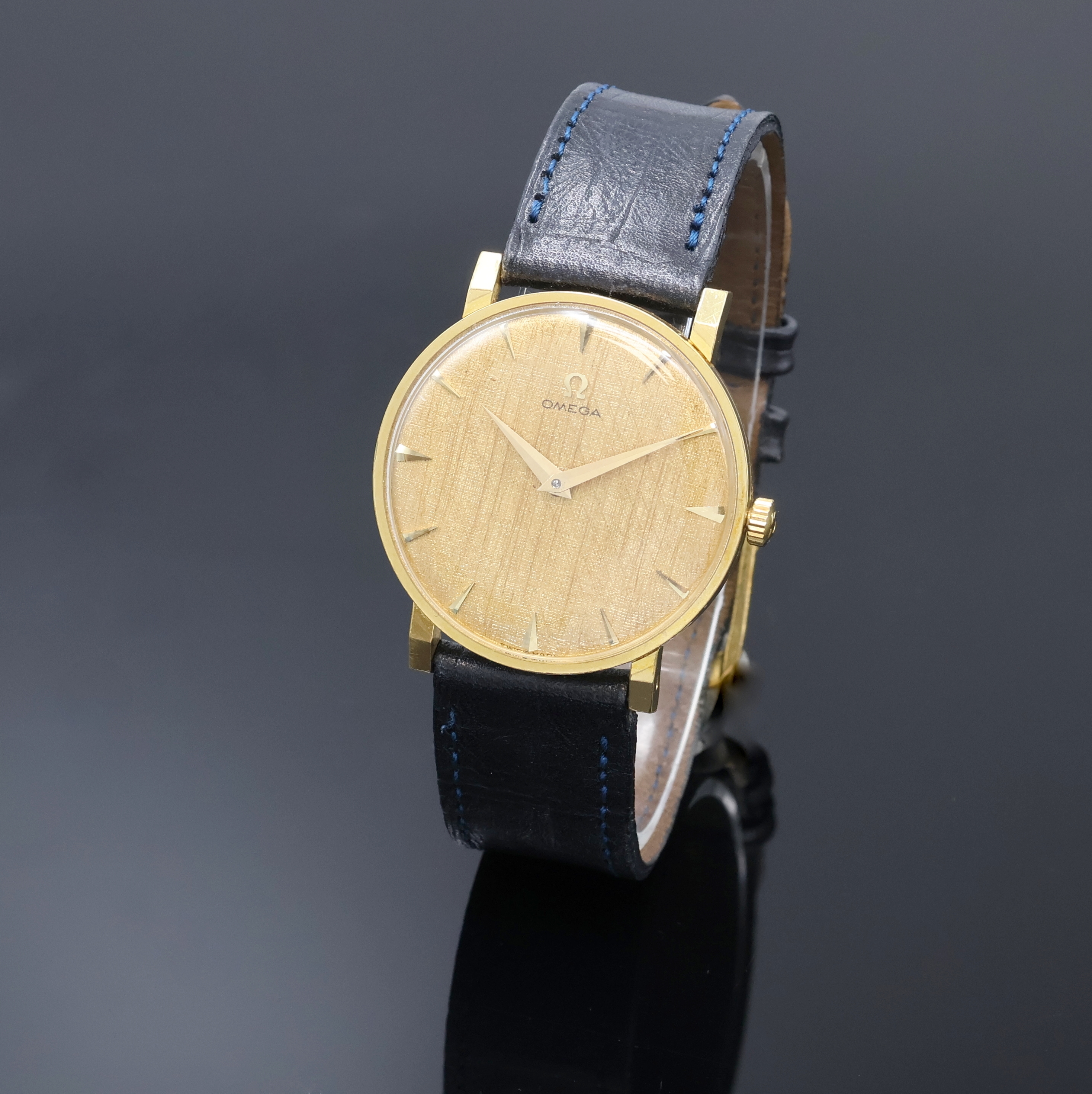 OMEGA Armbanduhr in GG 750/000 Referenz 14372, Schweiz um 1960, Handaufzug, Boden aufgedr., strukt. goldfarb. Zifferbl. m. gold. Std.-Ind. u. Zeiger, ...