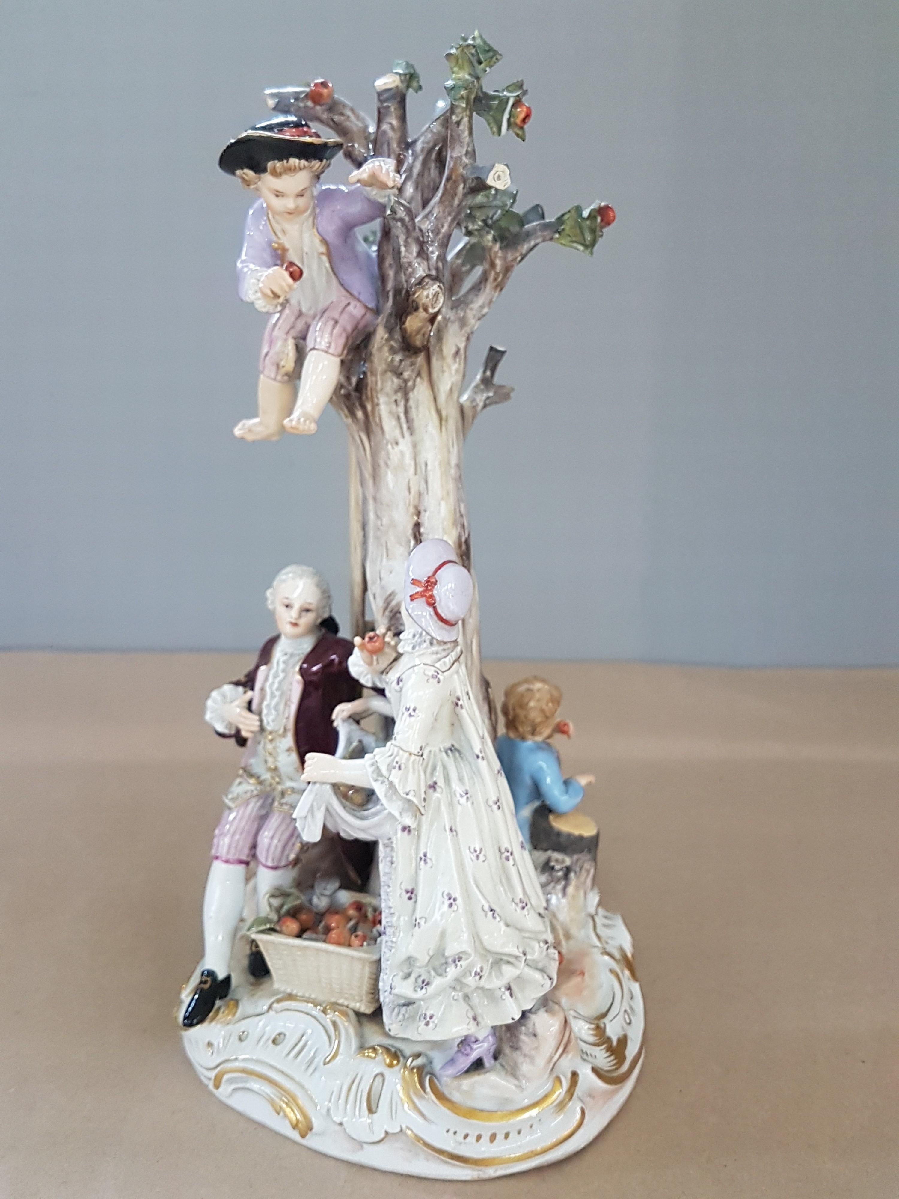 Detail b: Porzellangruppe, Meissen, um 1850-1924, Apfelernte, galantes Paar und zwei Knaben bei der Ernte, rest., bestoßen bzw. Fehlstellen im Baum, polychrom ...