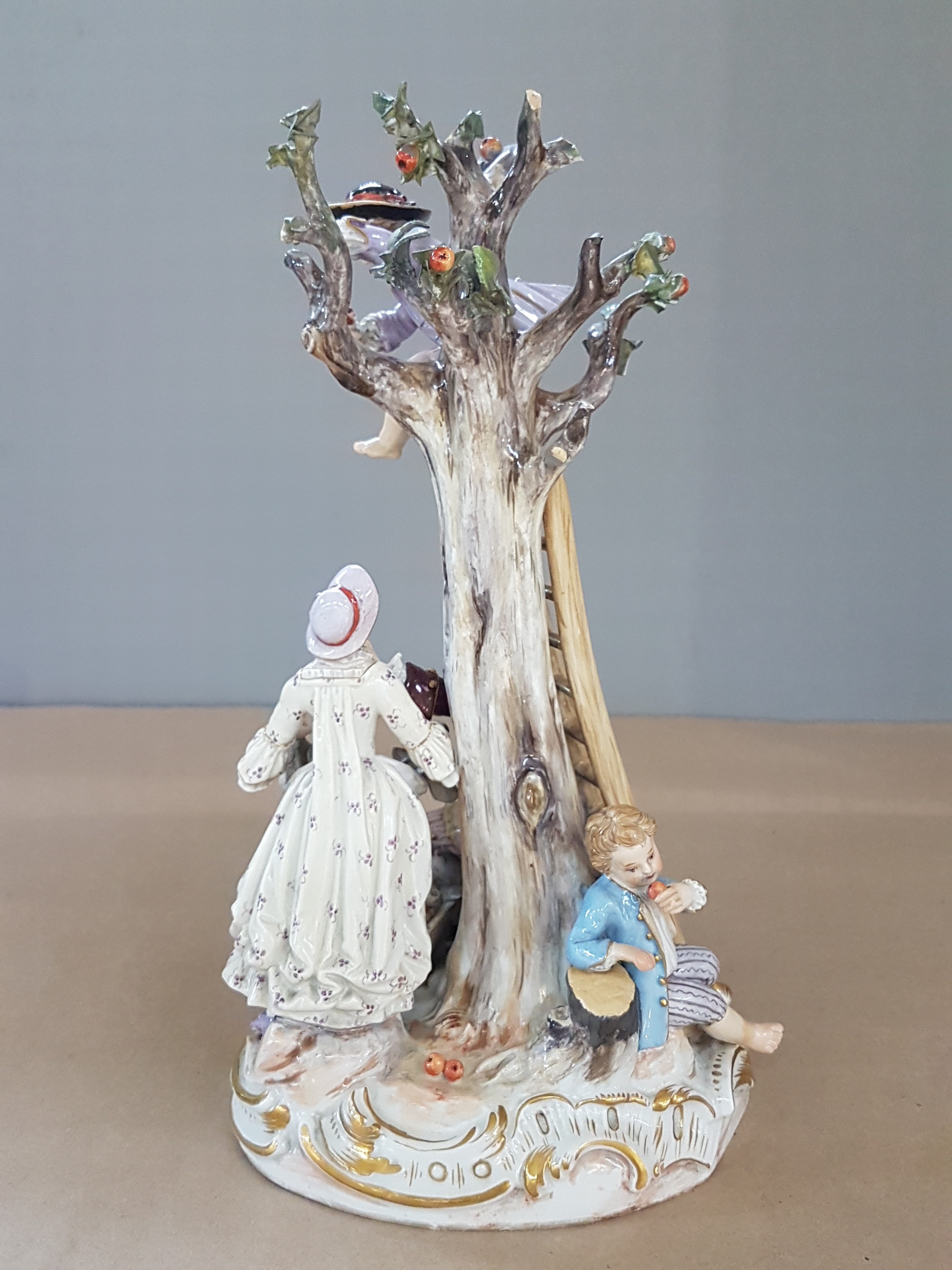 Detail c: Porzellangruppe, Meissen, um 1850-1924, Apfelernte, galantes Paar und zwei Knaben bei der Ernte, rest., bestoßen bzw. Fehlstellen im Baum, polychrom ...