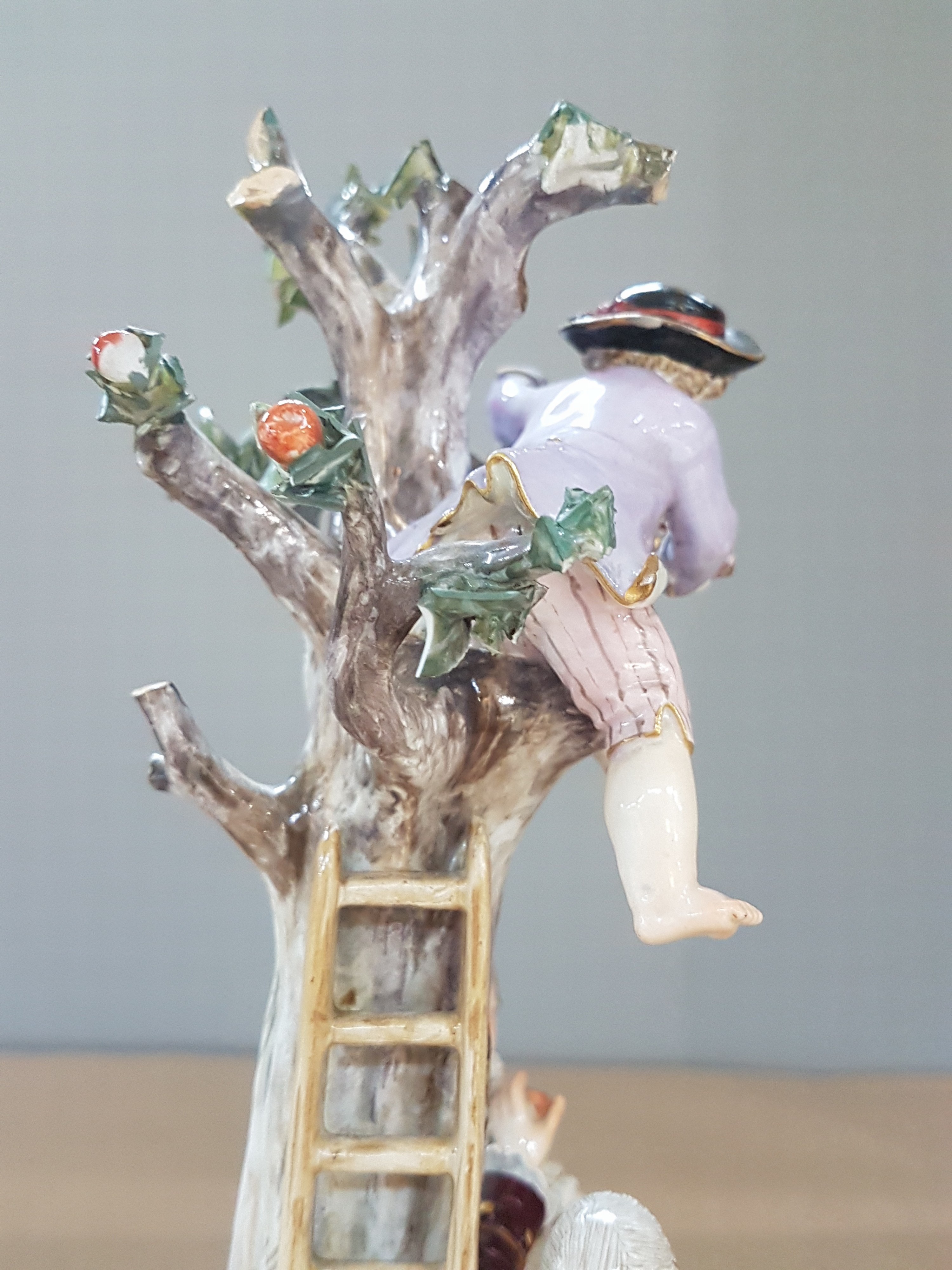 Detail i: Porzellangruppe, Meissen, um 1850-1924, Apfelernte, galantes Paar und zwei Knaben bei der Ernte, rest., bestoßen bzw. Fehlstellen im Baum, polychrom ...