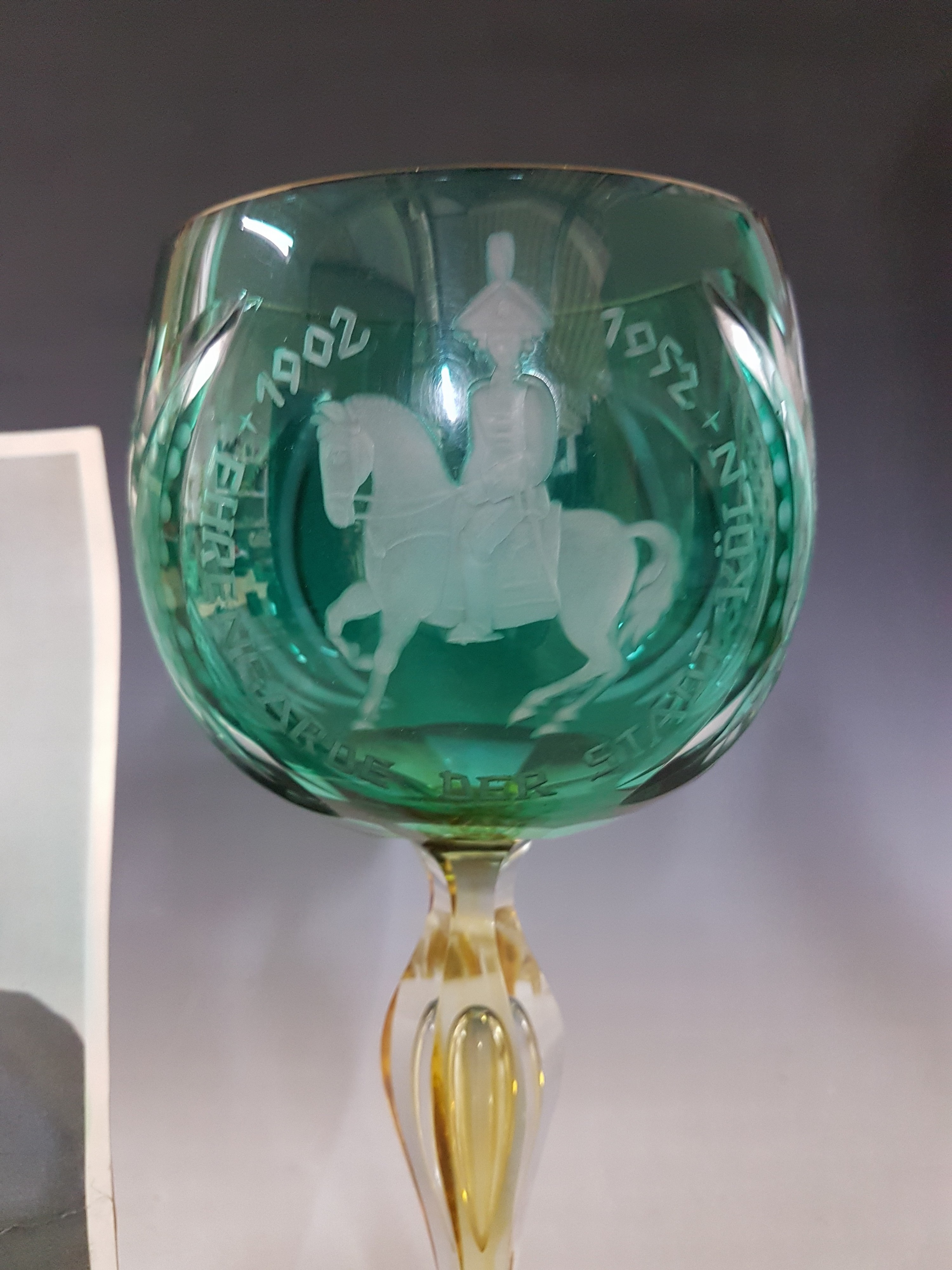 Detail b: Pokal der Ehrengarde der Stadt Köln, 1952, Kristallglas, Fuß gelb, Kuppa grün überfangen geschnitten und geschliffen, Inschrift, Goldrand, H. ca. ...