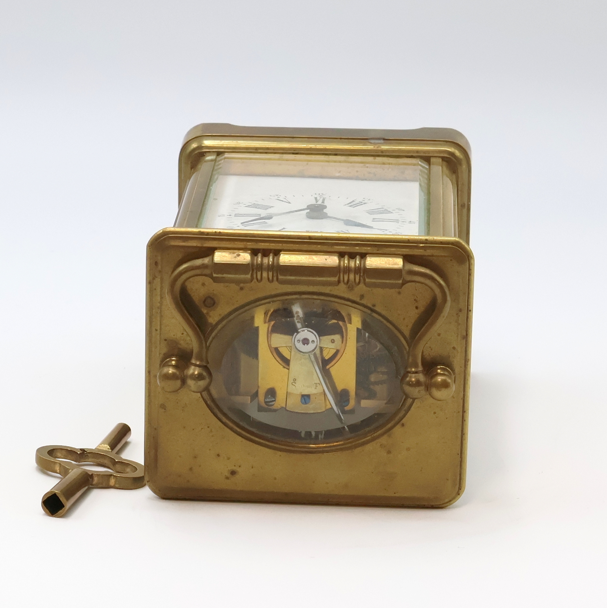 Detail e: Französische 8-Tage Reiseuhr in 5-seitig verglastem Messinggehäuse, um 1900, schlichtes Geh. m. Tragebügel, facett-vergl., rücks. zu öffnen f. ...