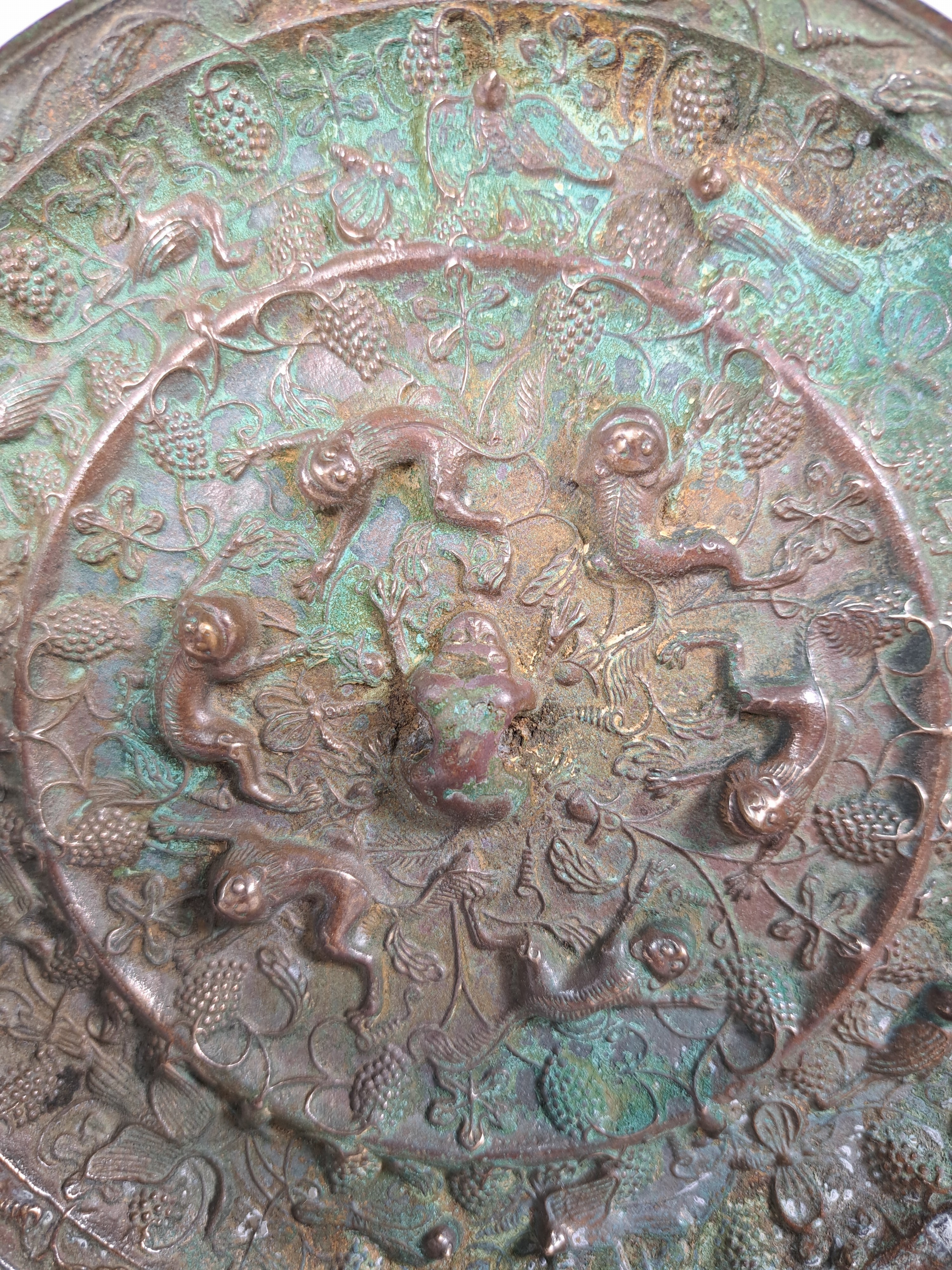 Detail b: Bronzespiegel, im Stil der Han-Dynastie, reliefiert mit Traubendekor und Tieren, D. ca. 19 cm
