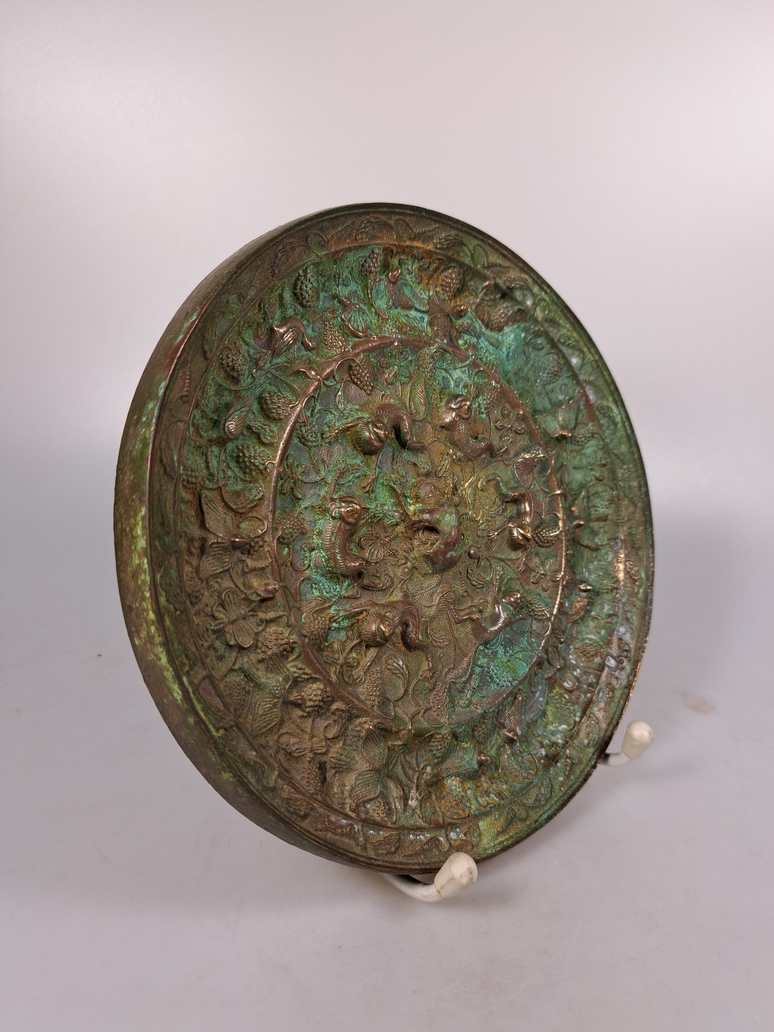 Detail c: Bronzespiegel, im Stil der Han-Dynastie, reliefiert mit Traubendekor und Tieren, D. ca. 19 cm