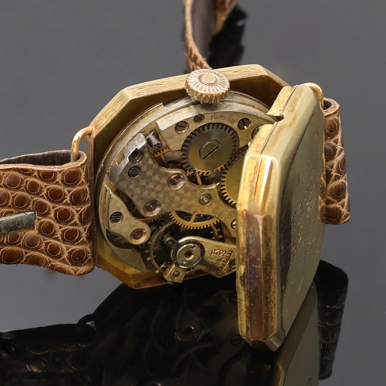 Detail d: Armbanduhr in GG 750/000 an Lederband, Schweiz um 1935, Handaufzug, 8-eckiges, grav. Scharniergeh., gold. Zifferbl. fl./pat., gebl. Zeiger, vern. ...