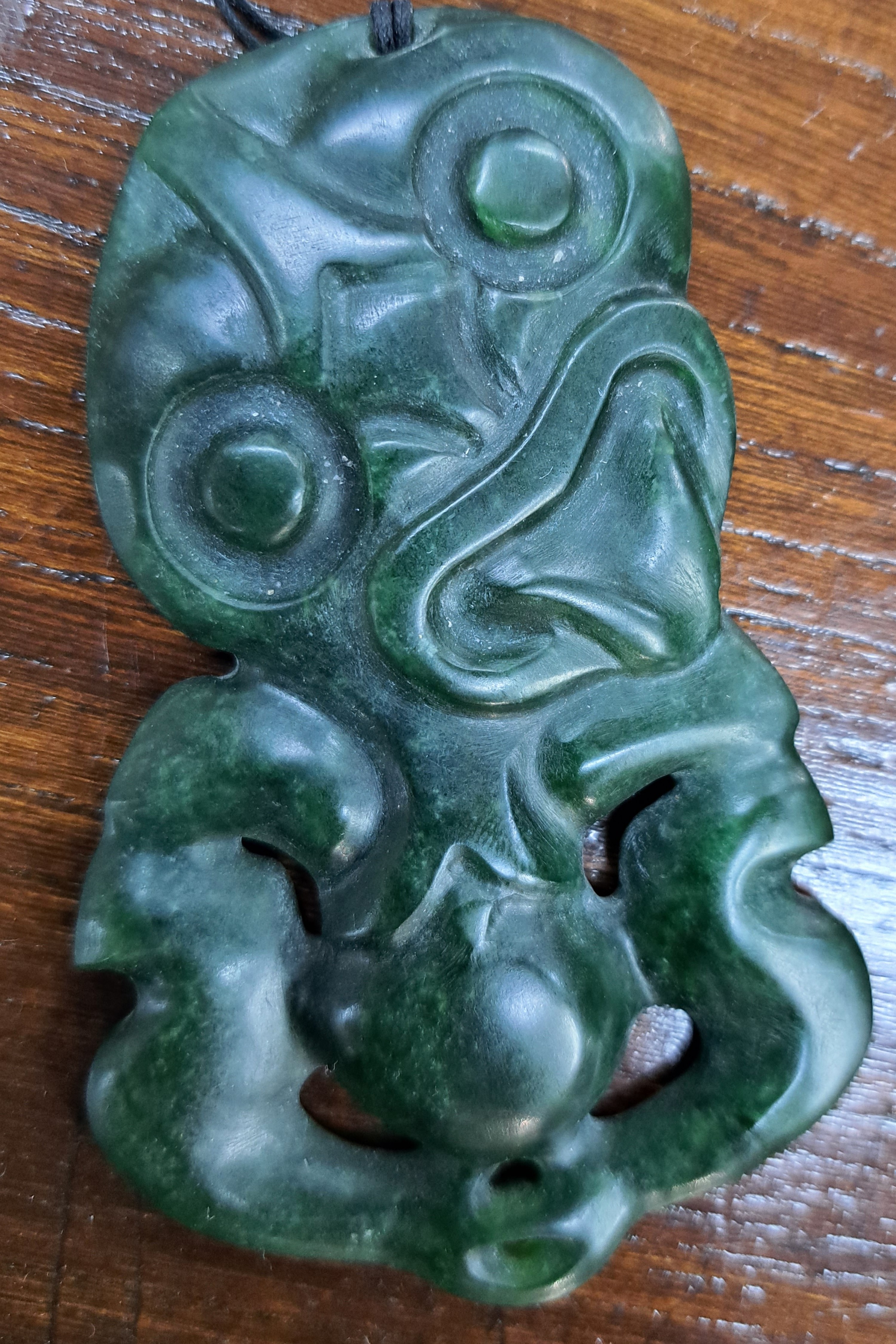 Detail a: Hei Tiki, Amulett der Maori, Neuseeland, Nephrit, sog. Greenstone, geschnitzt und geritzt, 9x5,5 cm, mit Lederband