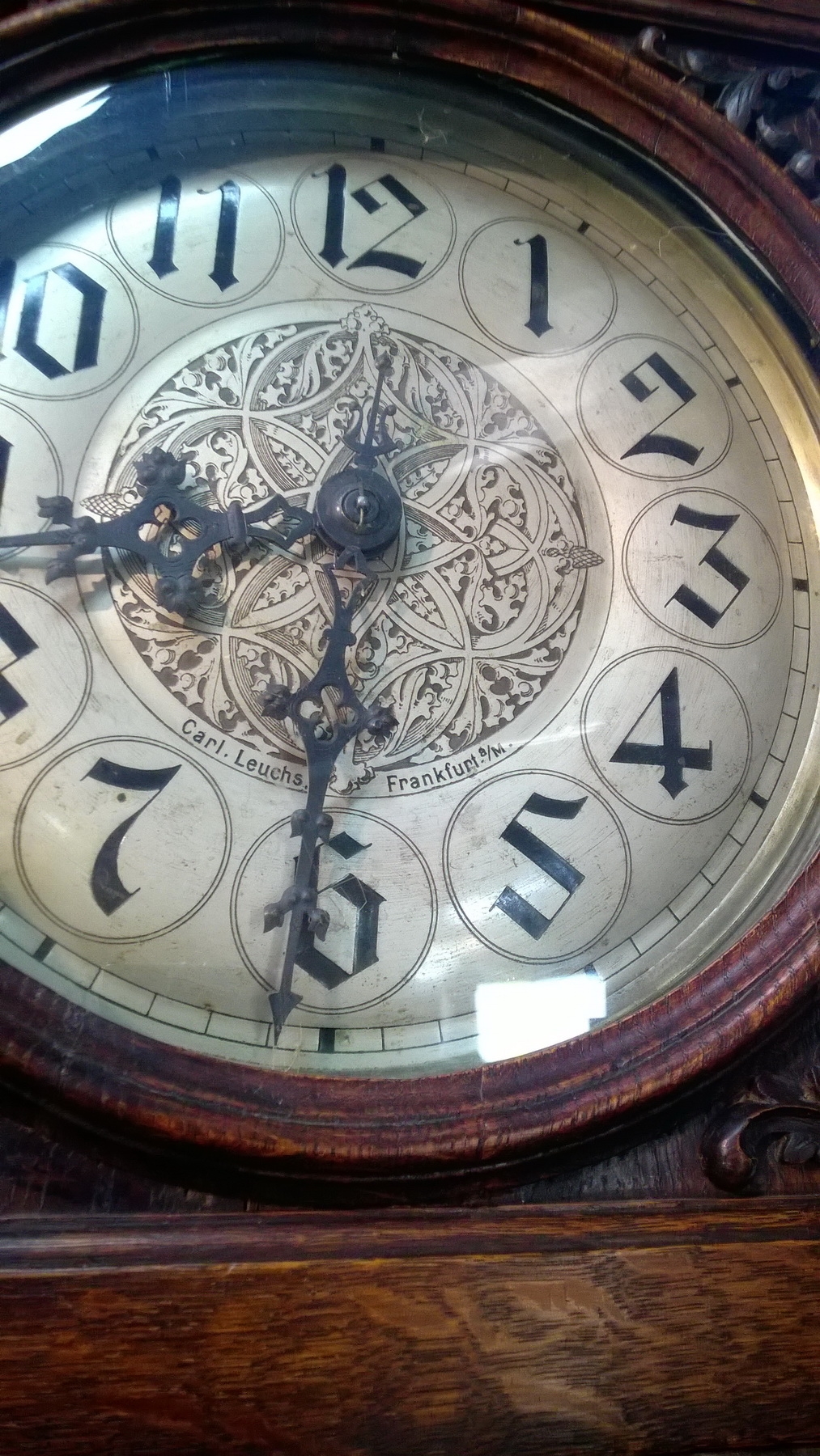Detail b: Standuhr, Jugendstil, Gustav Becker,von 1901 , florale Flachschnitzereien, Holzgehäuse, offener Schwungbereich des Pendels, verzierte Pendelscheibe ...