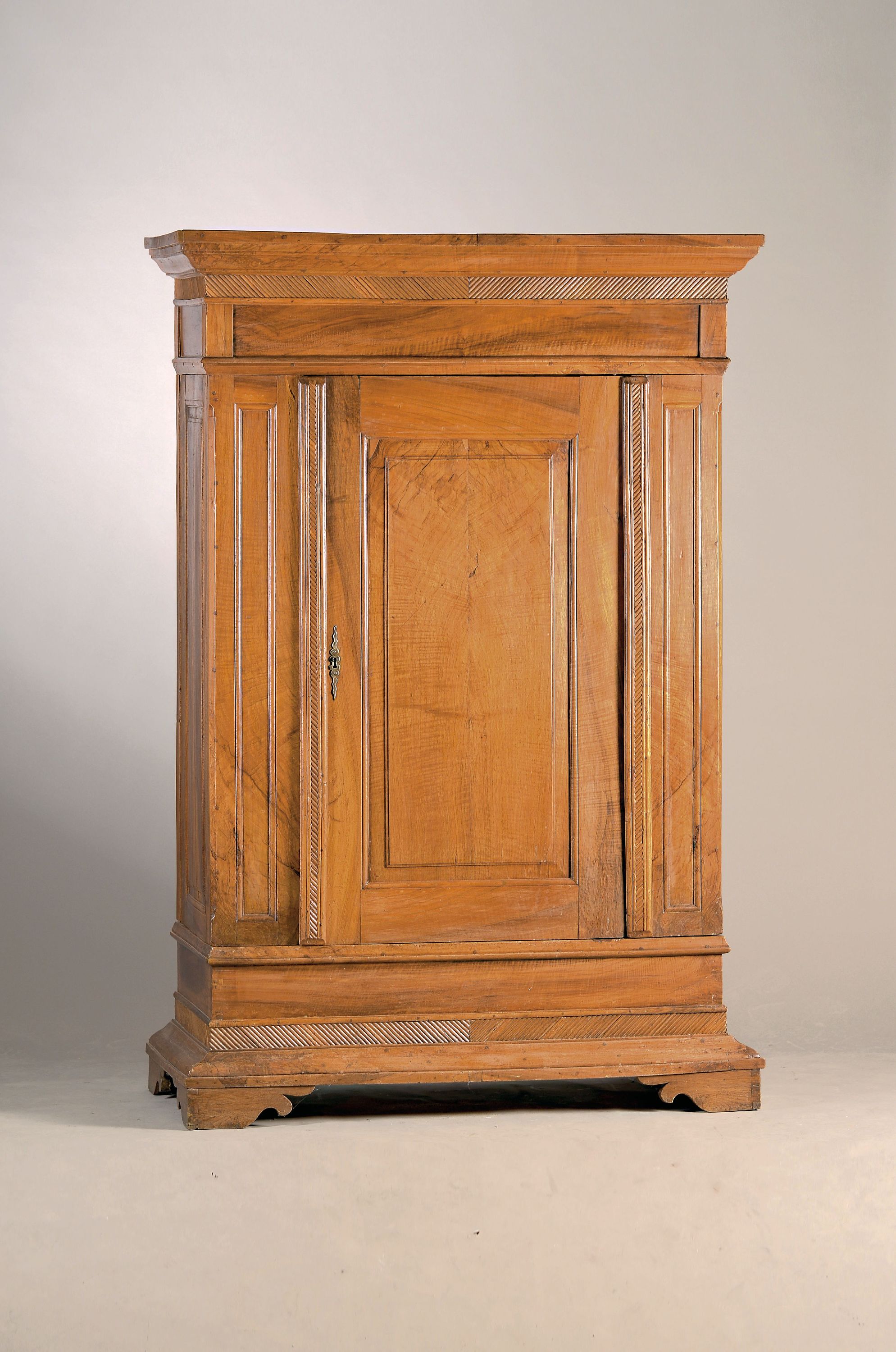 Eintüriger Schrank, um 1860, Nußbaum massiv und furniert, aufgelegte beschnitzte Lisenen, innen drei Fachböden, ca. 195x130x62cm, EZ 3, 1 ...