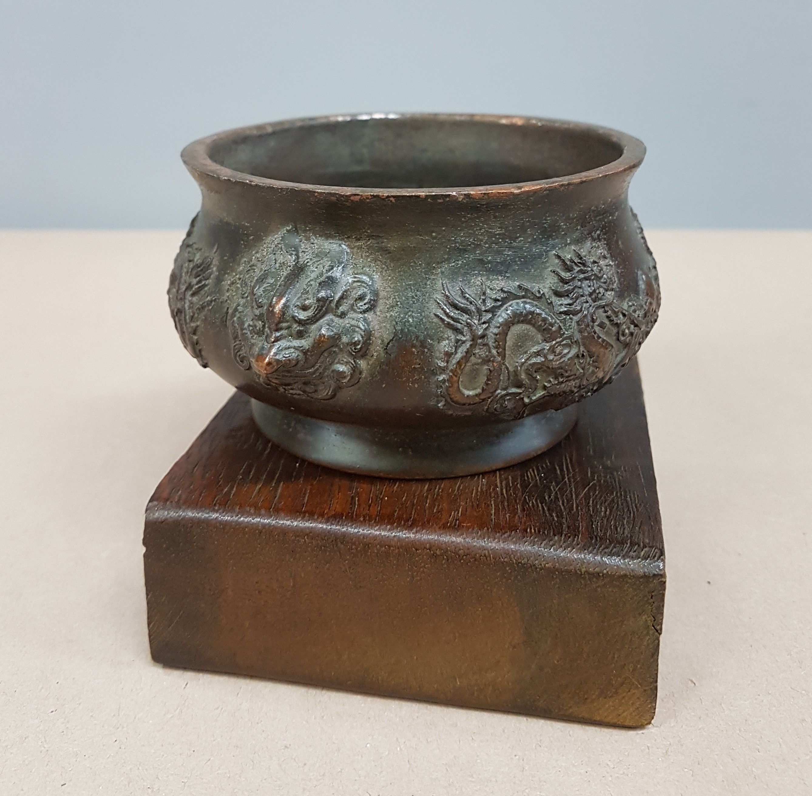 Detail b: kleines Räuchergefäß, China, um 1900, Bronze, umlaufender Drachendekor, dazu geschnitzter Holzsockel (später), D. ca. 11.5 cm, H. ca. 5.5 cm, mit ...