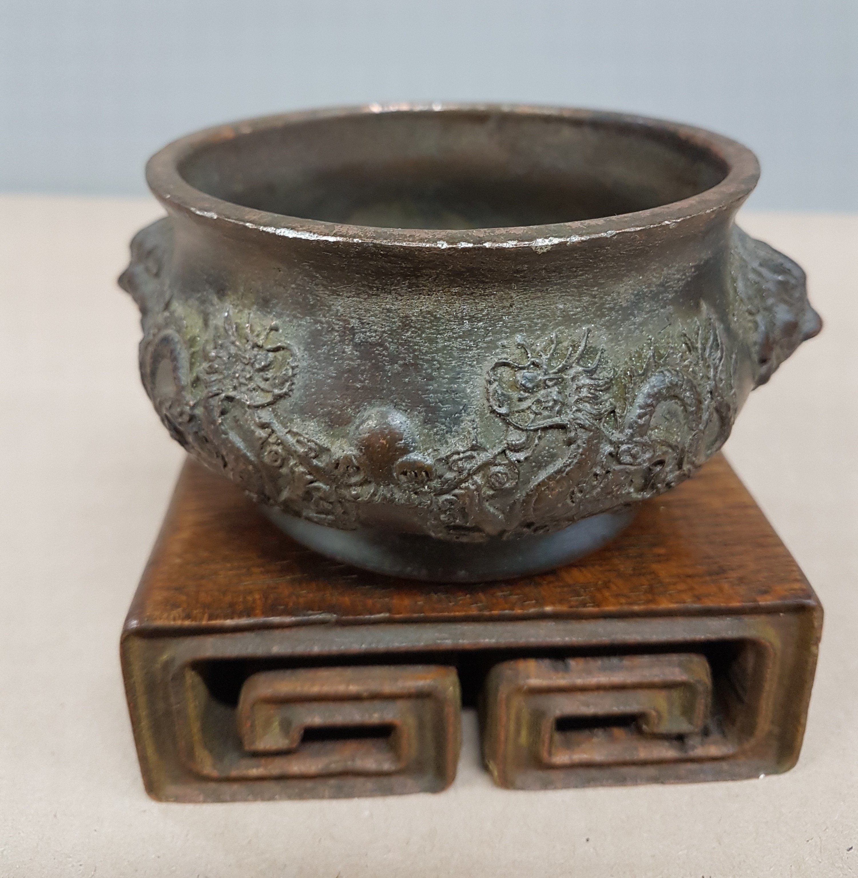 Detail c: kleines Räuchergefäß, China, um 1900, Bronze, umlaufender Drachendekor, dazu geschnitzter Holzsockel (später), D. ca. 11.5 cm, H. ca. 5.5 cm, mit ...