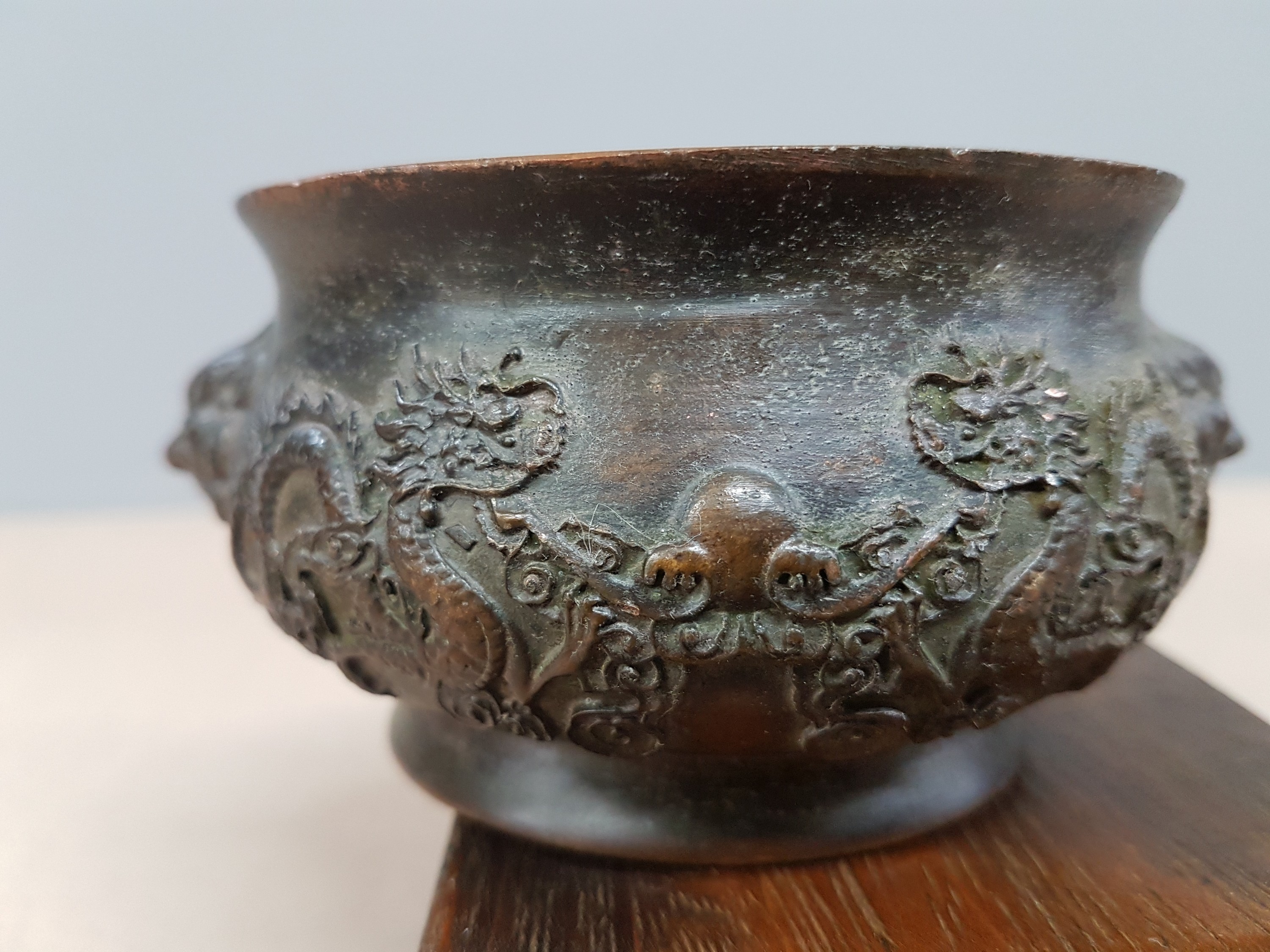 Detail e: kleines Räuchergefäß, China, um 1900, Bronze, umlaufender Drachendekor, dazu geschnitzter Holzsockel (später), D. ca. 11.5 cm, H. ca. 5.5 cm, mit ...