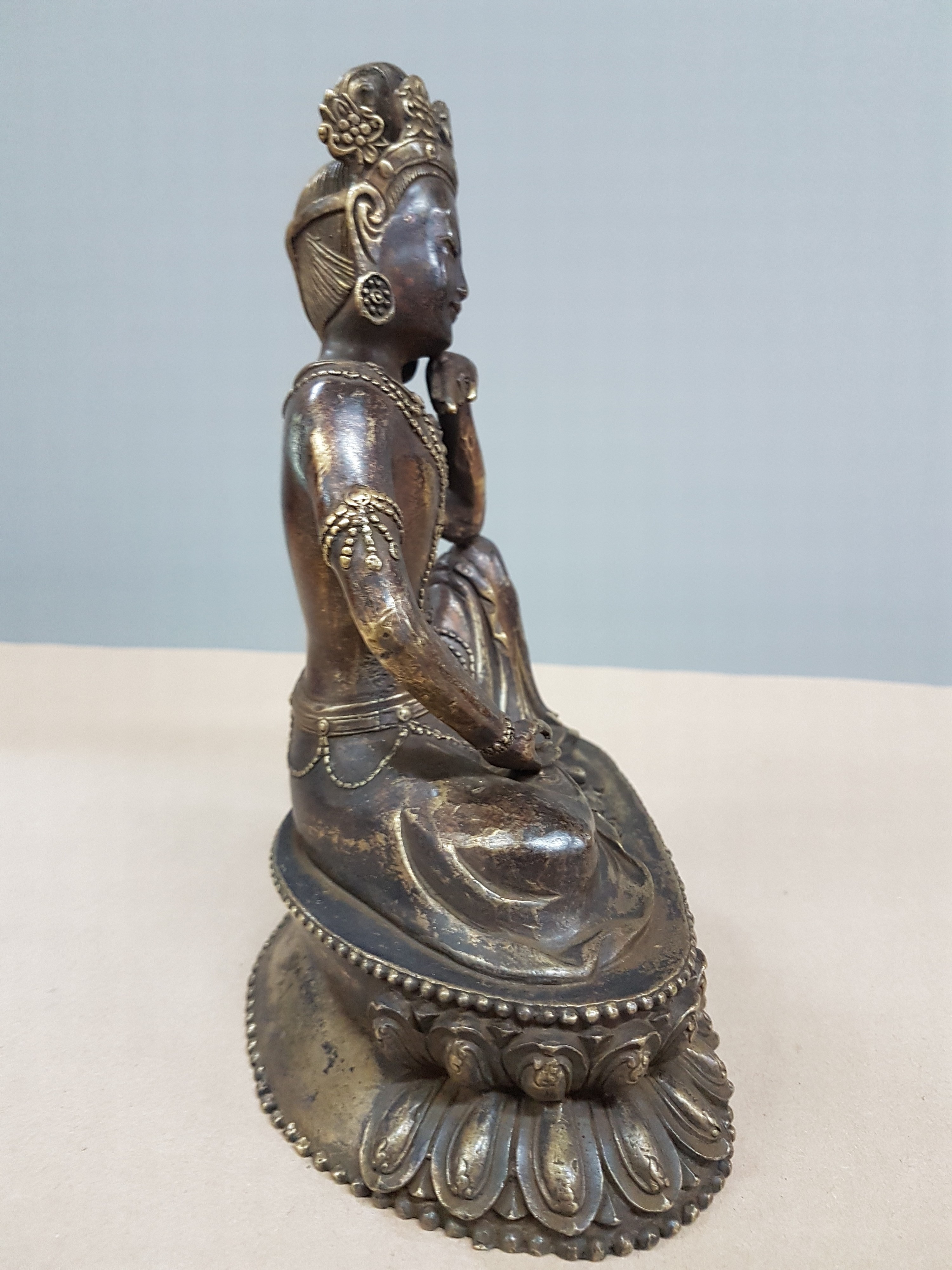 Detail b: Buddha, Tibet, 20. Jh., Bronze, patiniert, auf Lotussockel, eine Hand aufgestützt, H. ca. 21 cm
